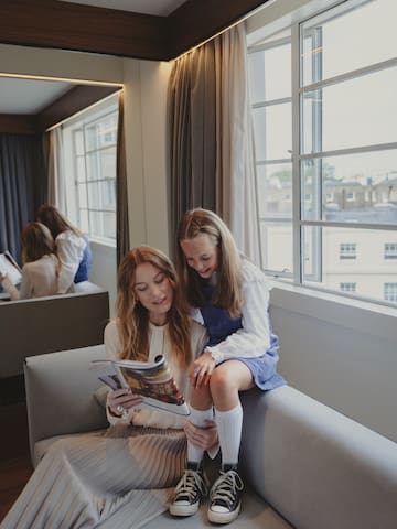 a woman and a girl sitting on a couch reading a magazine