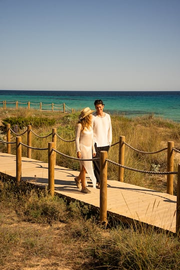 a man and woman walking on a wooden walkway by the water