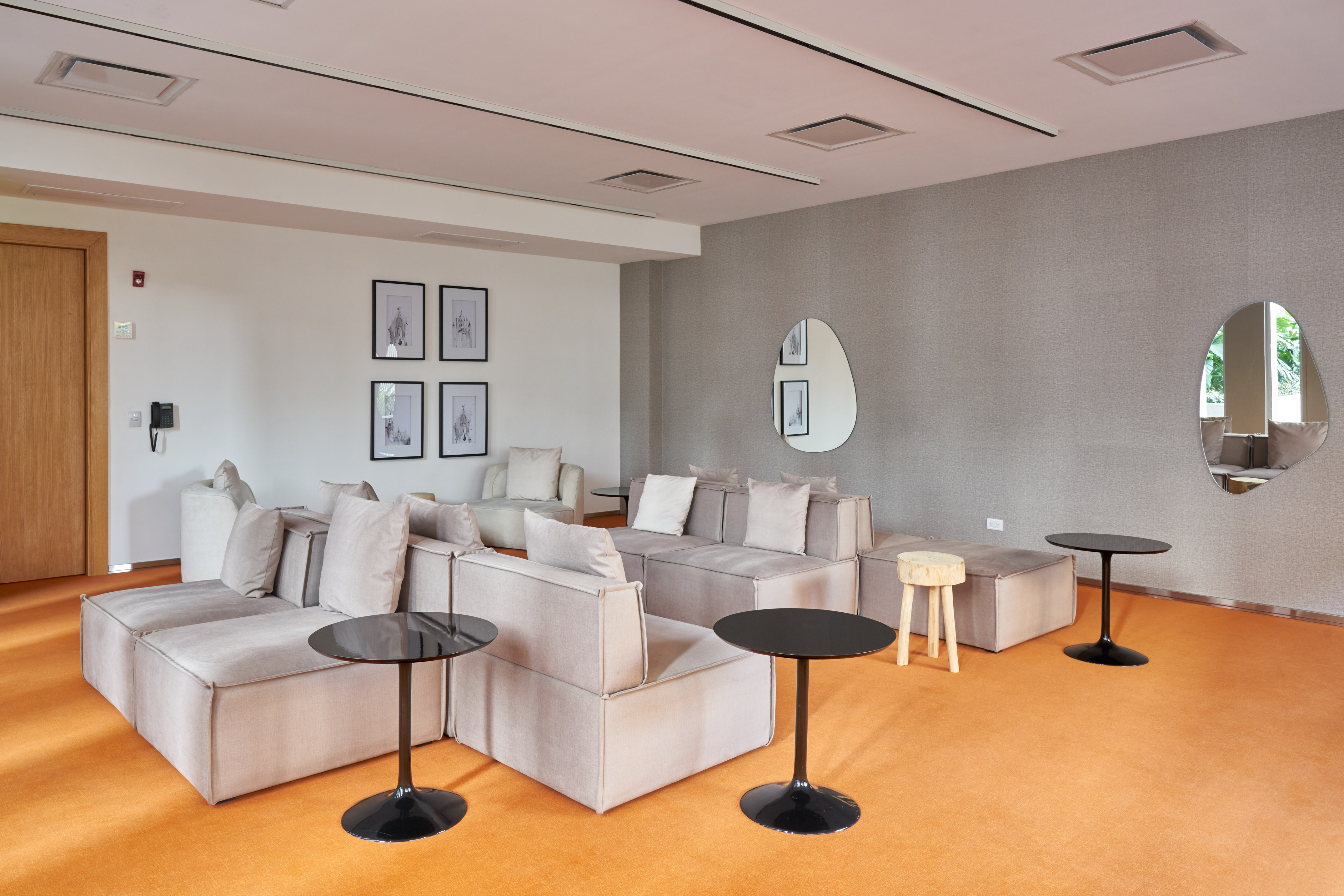 Contemporary lounge with grey modular sofas, orange carpet, and modern decor.