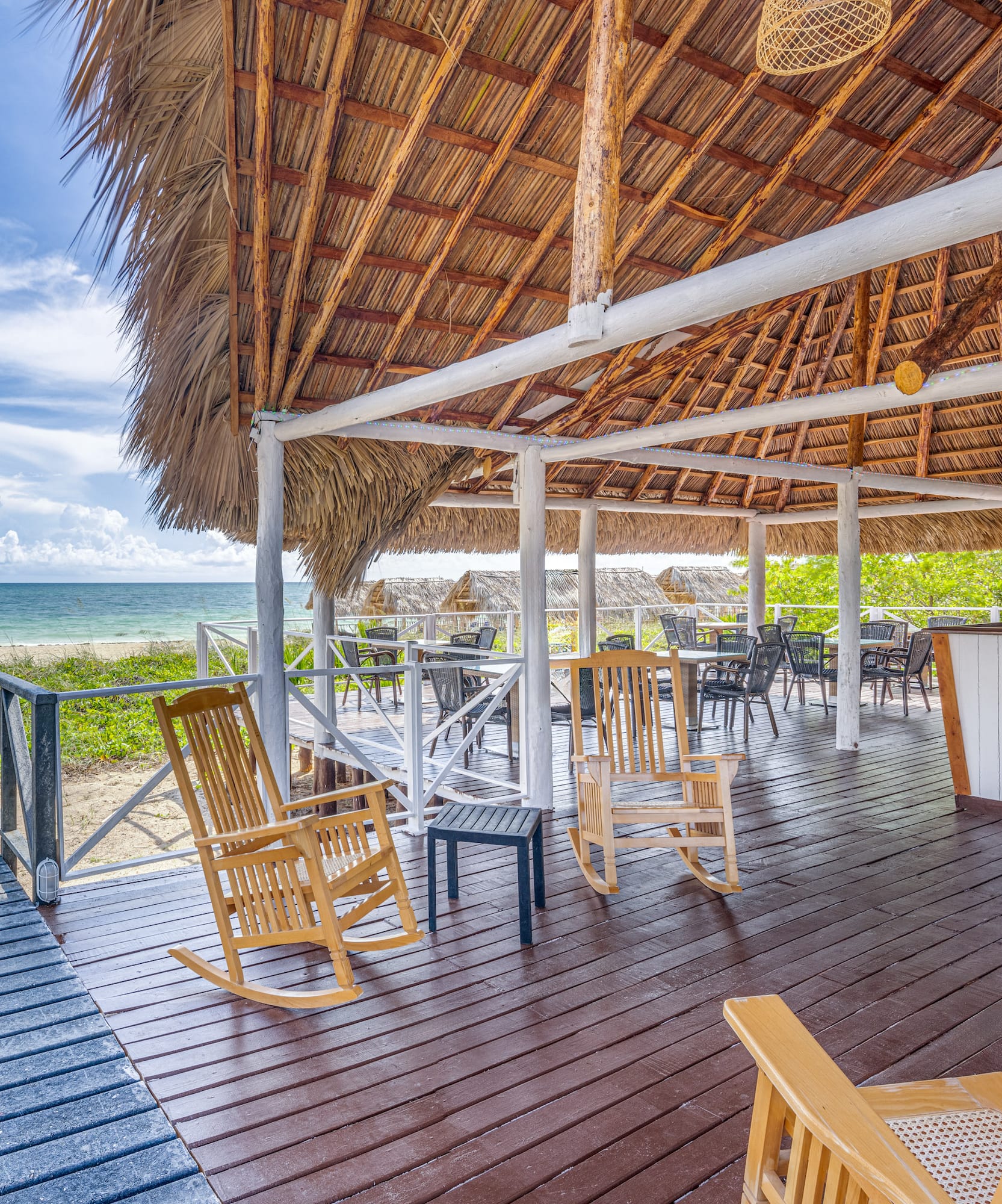 a deck with chairs and a thatched roof