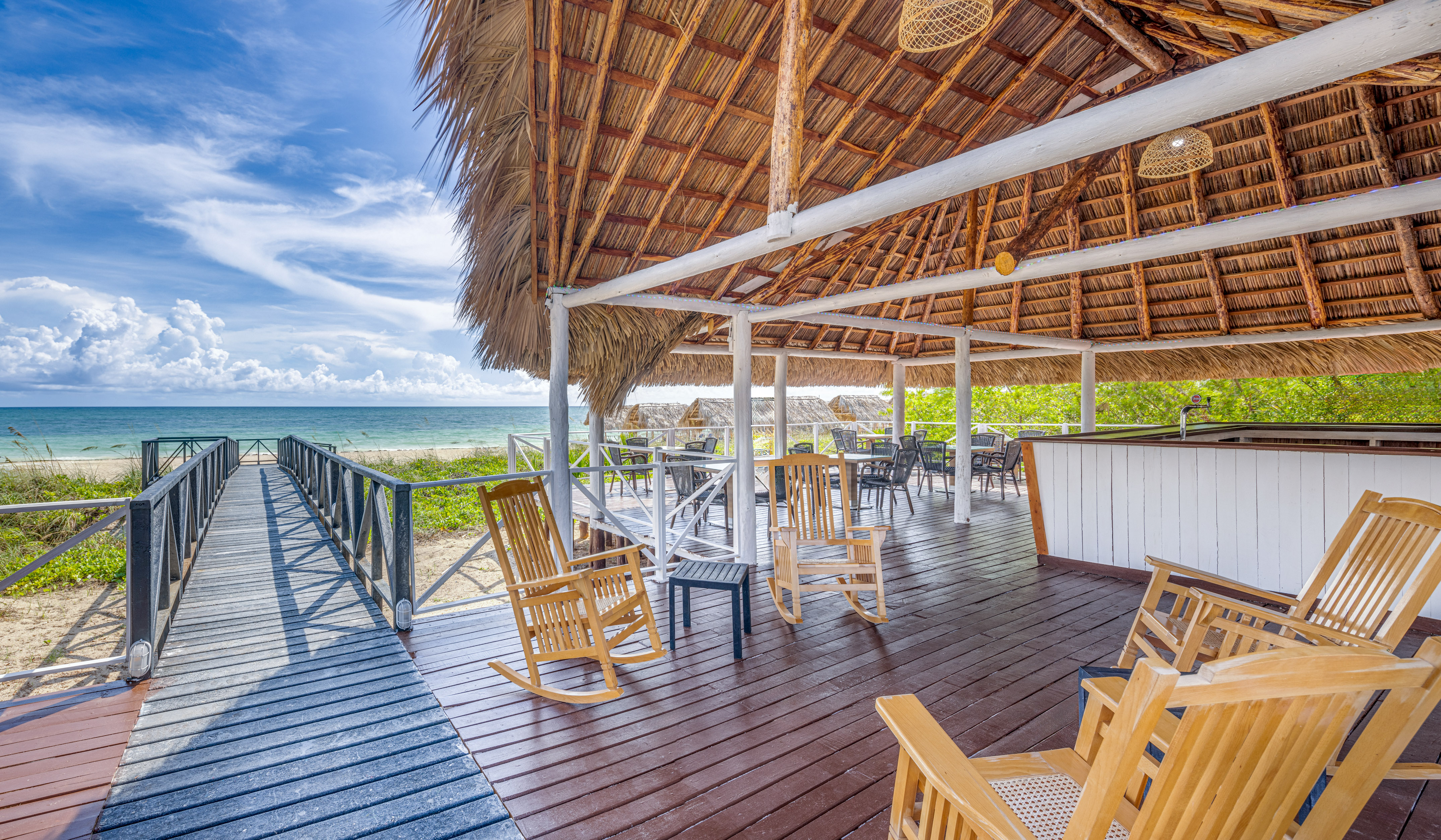 a deck with chairs and a thatched roof