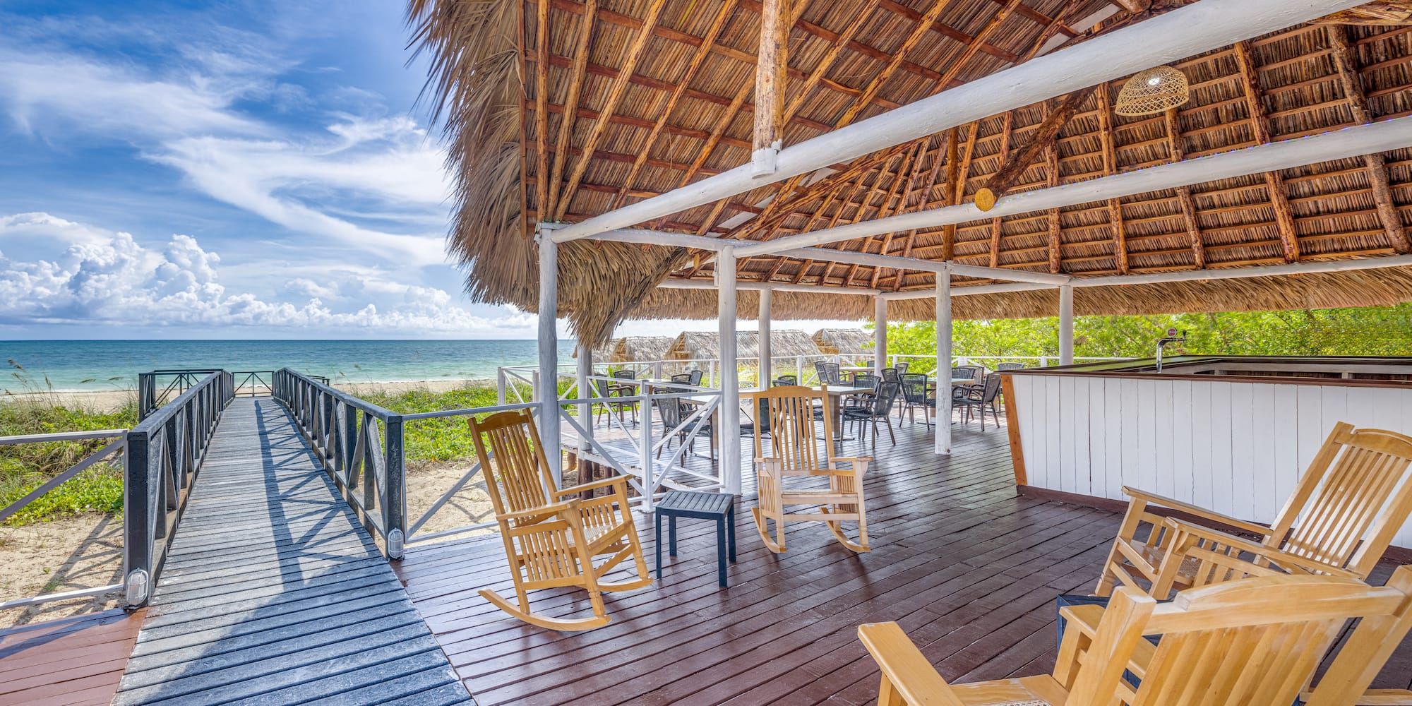 a deck with chairs and a thatched roof