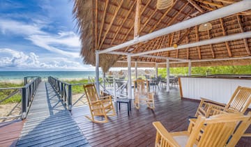 a deck with chairs and a thatched roof