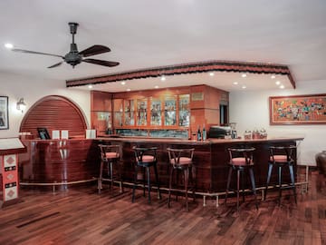 a bar with stools and a ceiling fan