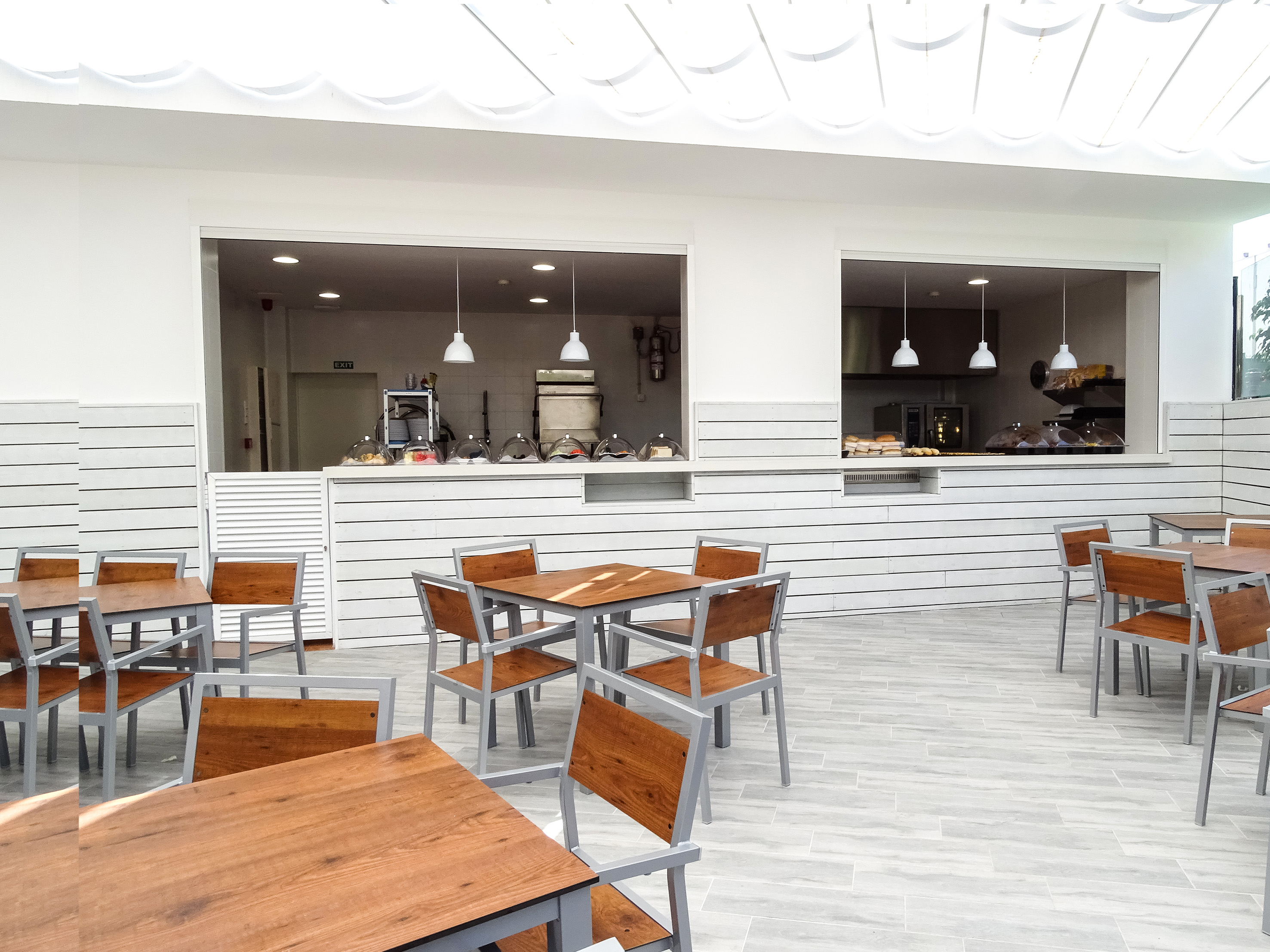 Bright modern buffet dining space with wood tables and serving counter.