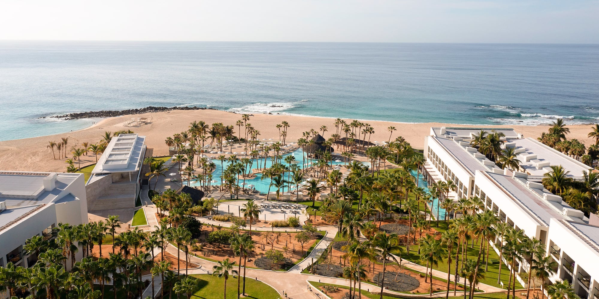 Aerial view of luxury beachfront resort with large swimming pool, palm trees, and ocean. - Paradisus Los Cabos - Adults Only, Los Cabos