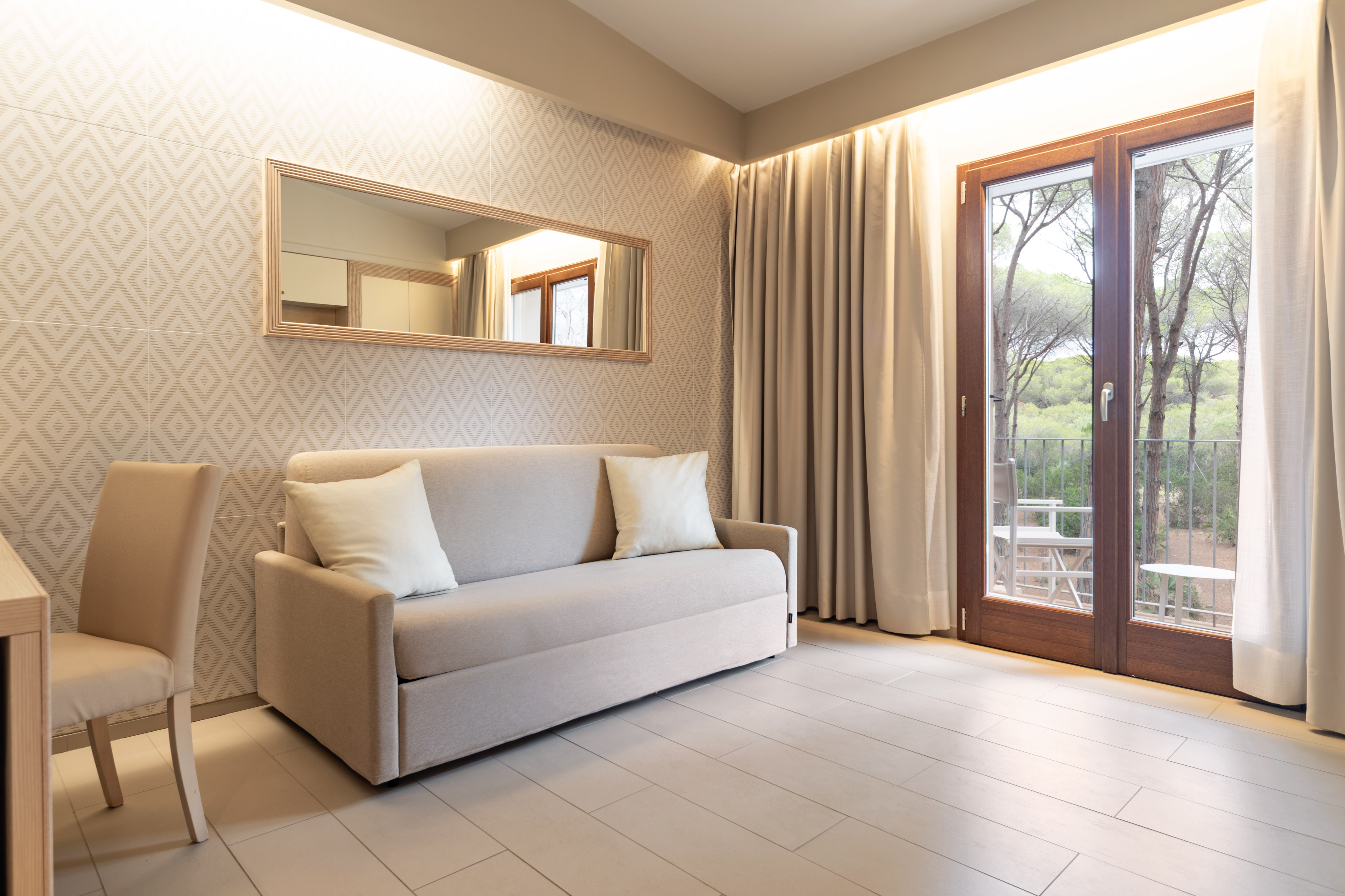 Modern living area with neutral sofa, mirror, and balcony view.