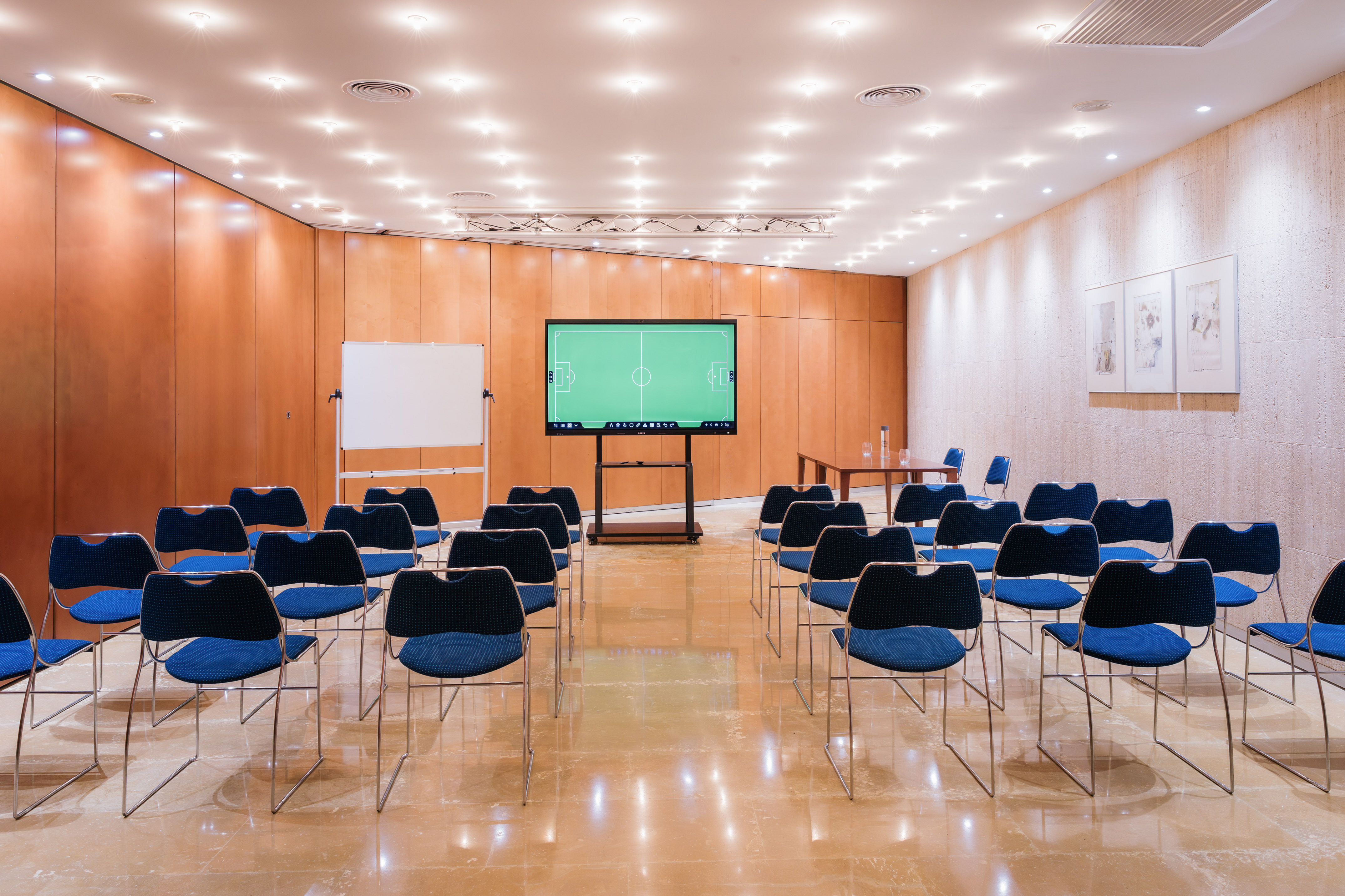 Empty modern conference room with blue chairs, presentation screen, and whiteboard.