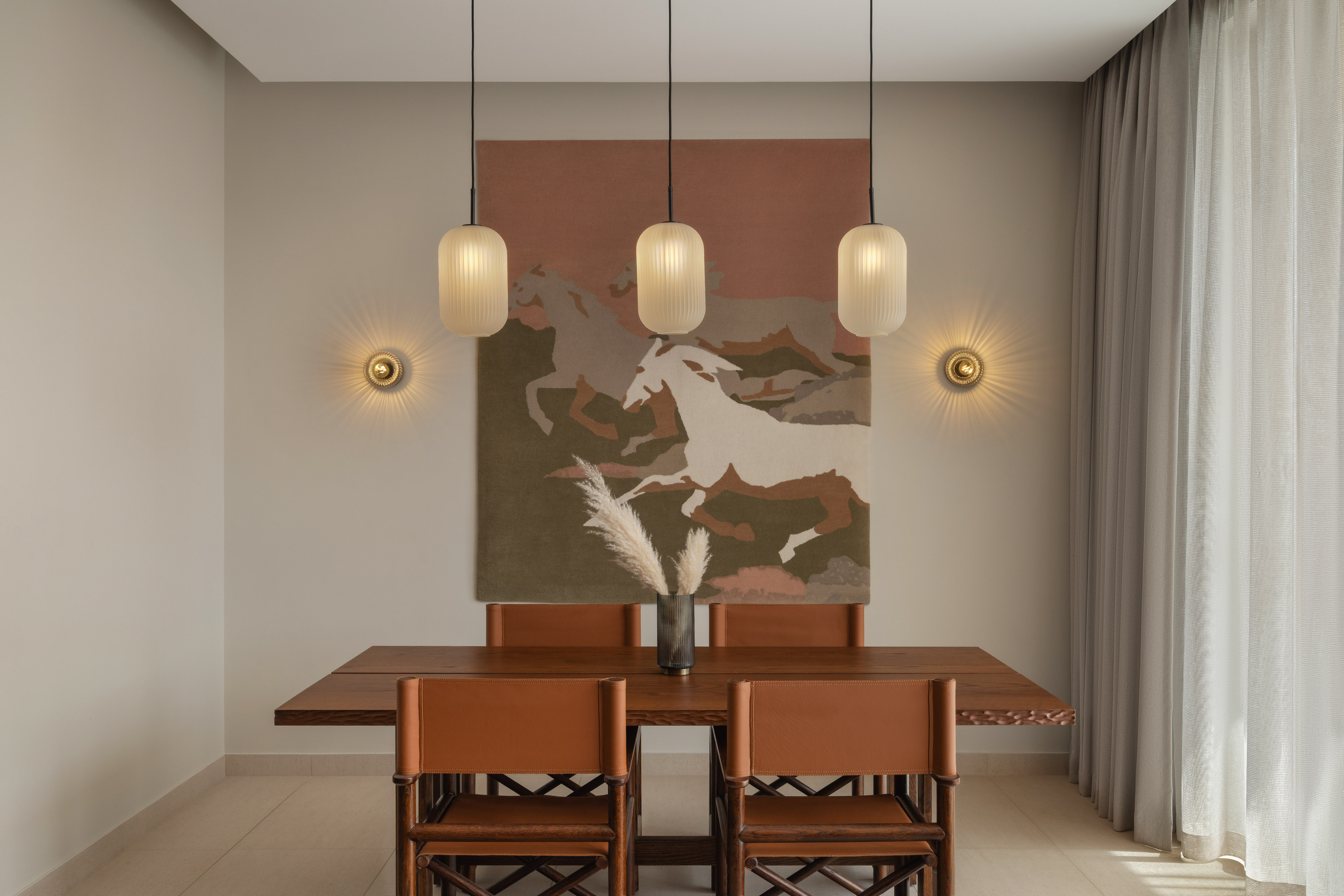 Modern dining room with wooden table, tan leather chairs, pendant lights, and horse art.
