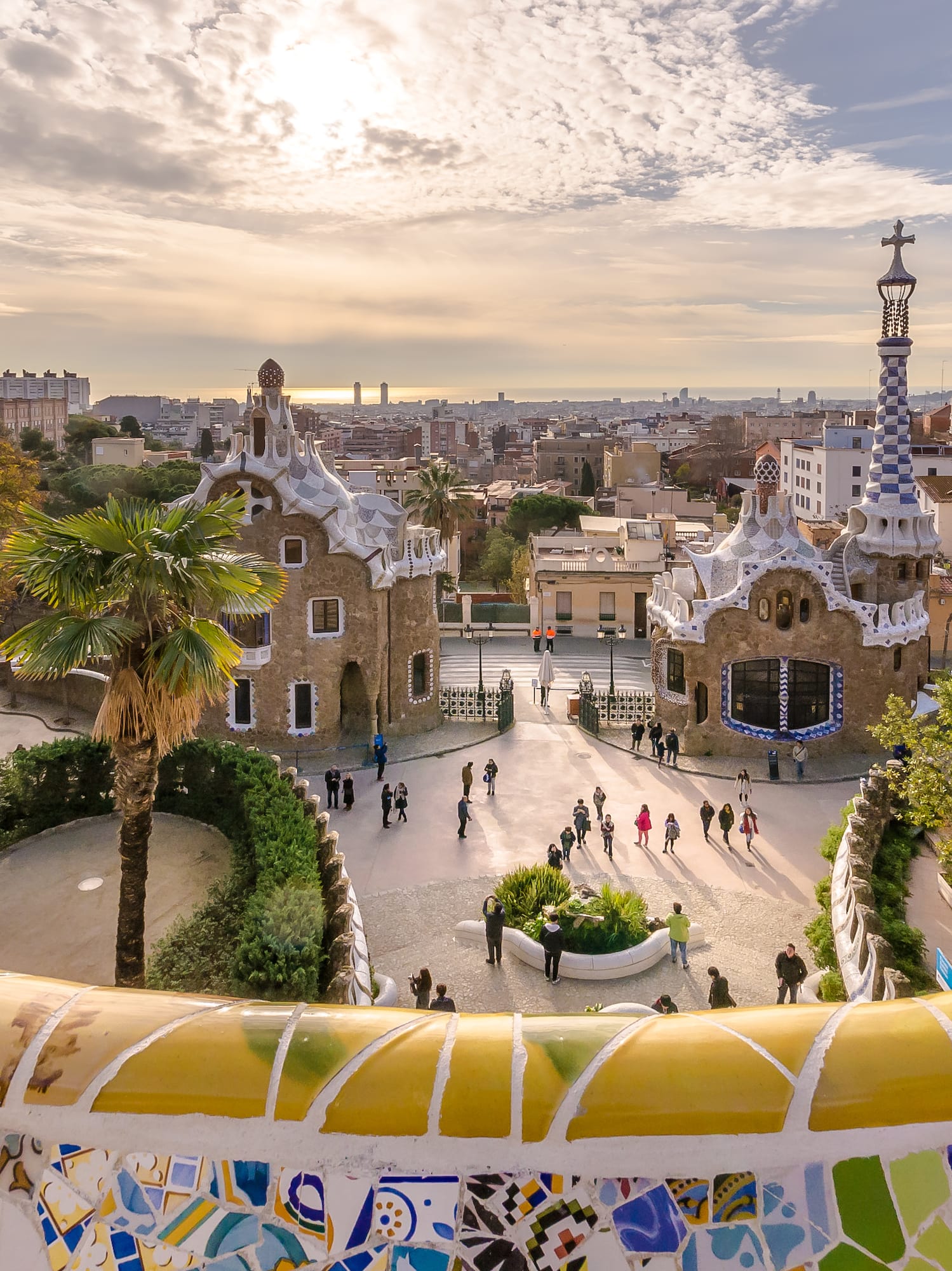 Park Güell Barcelona: mosaic bench, Gaudí gingerbread houses, city skyline.