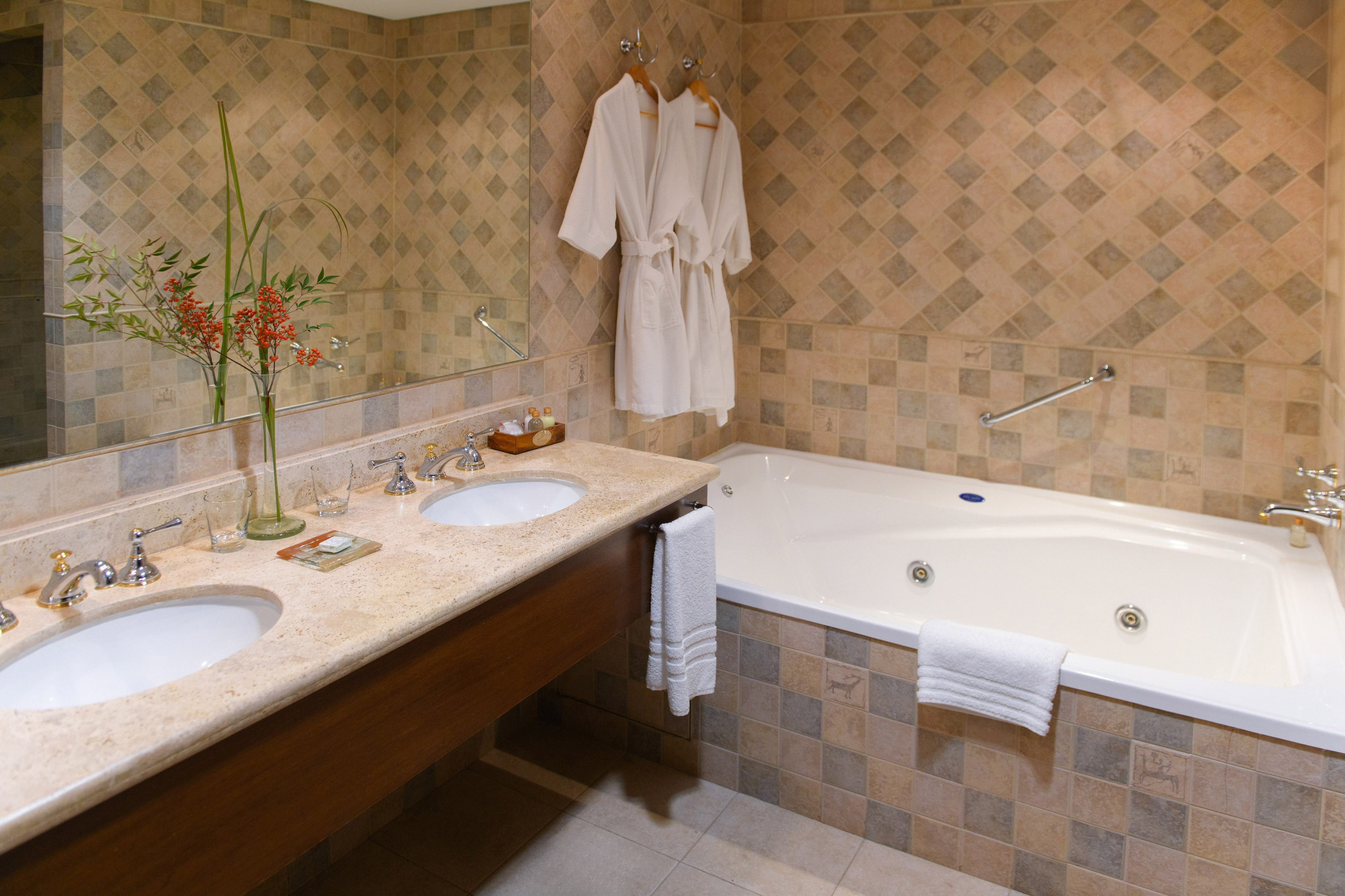Luxury hotel bathroom with double vanity, two robes, and jetted tub.