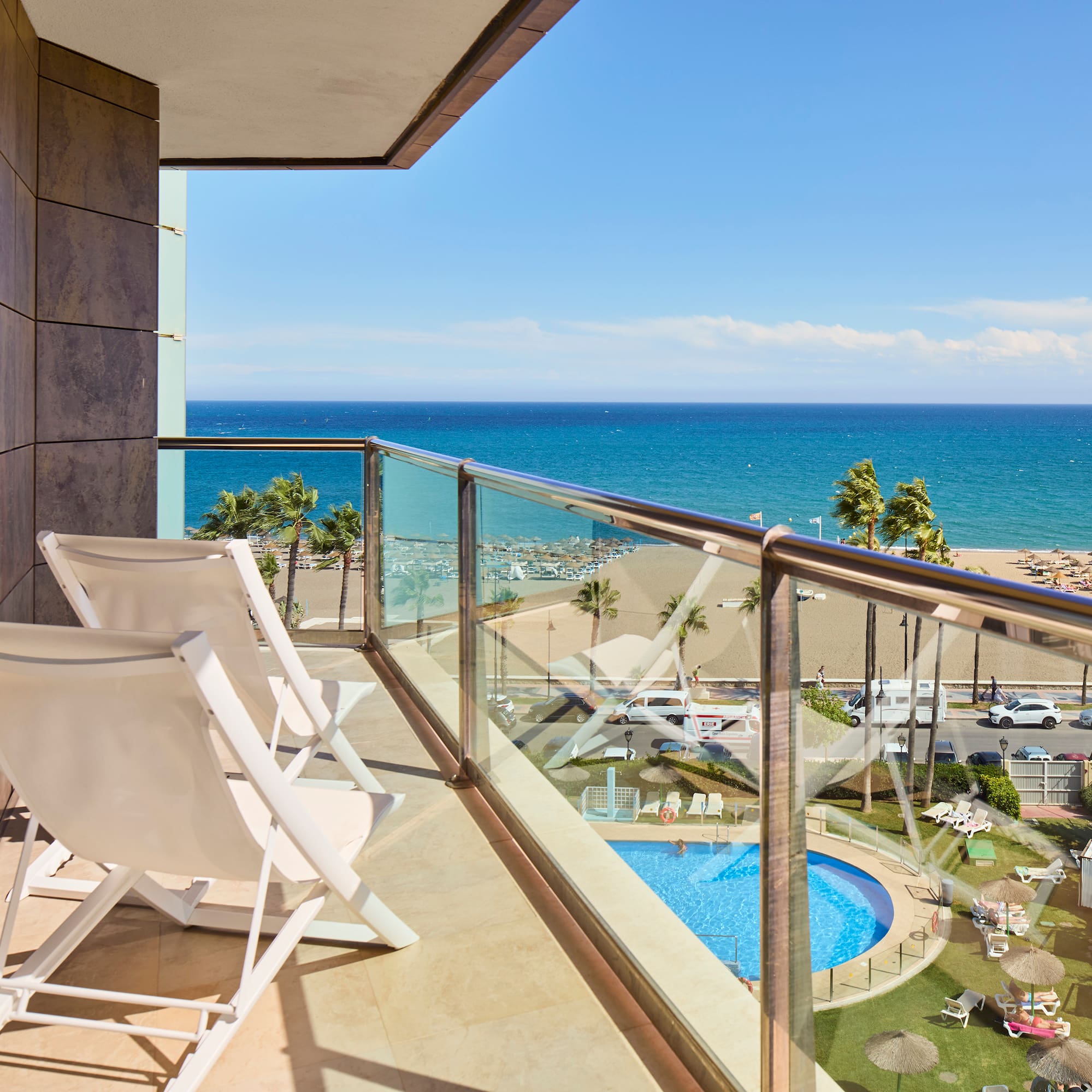 a balcony with chairs and a pool overlooking the ocean