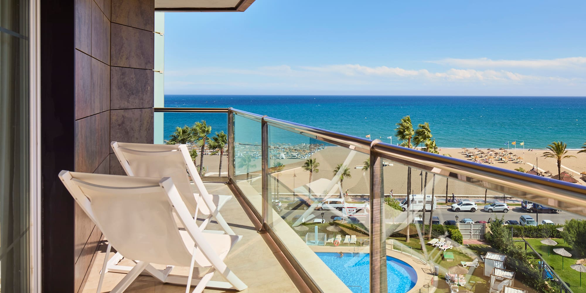 a balcony with chairs and a pool overlooking the ocean
