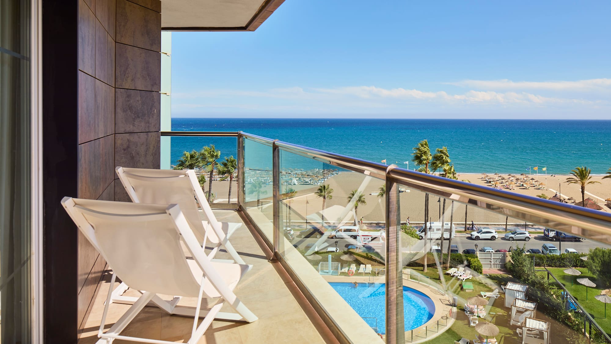 a balcony with chairs and a pool overlooking the ocean