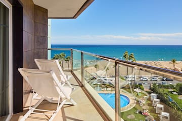 a balcony with chairs and a pool overlooking the ocean