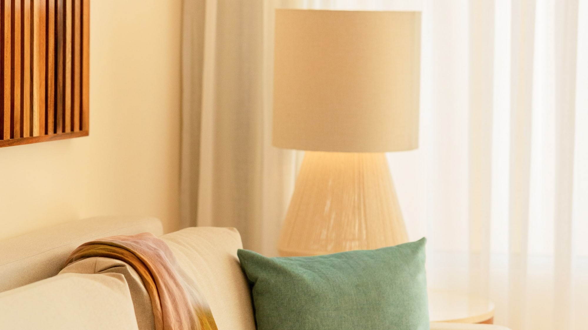 Cozy living room sofa with colorful throw, teal pillow, and soft lamp light.