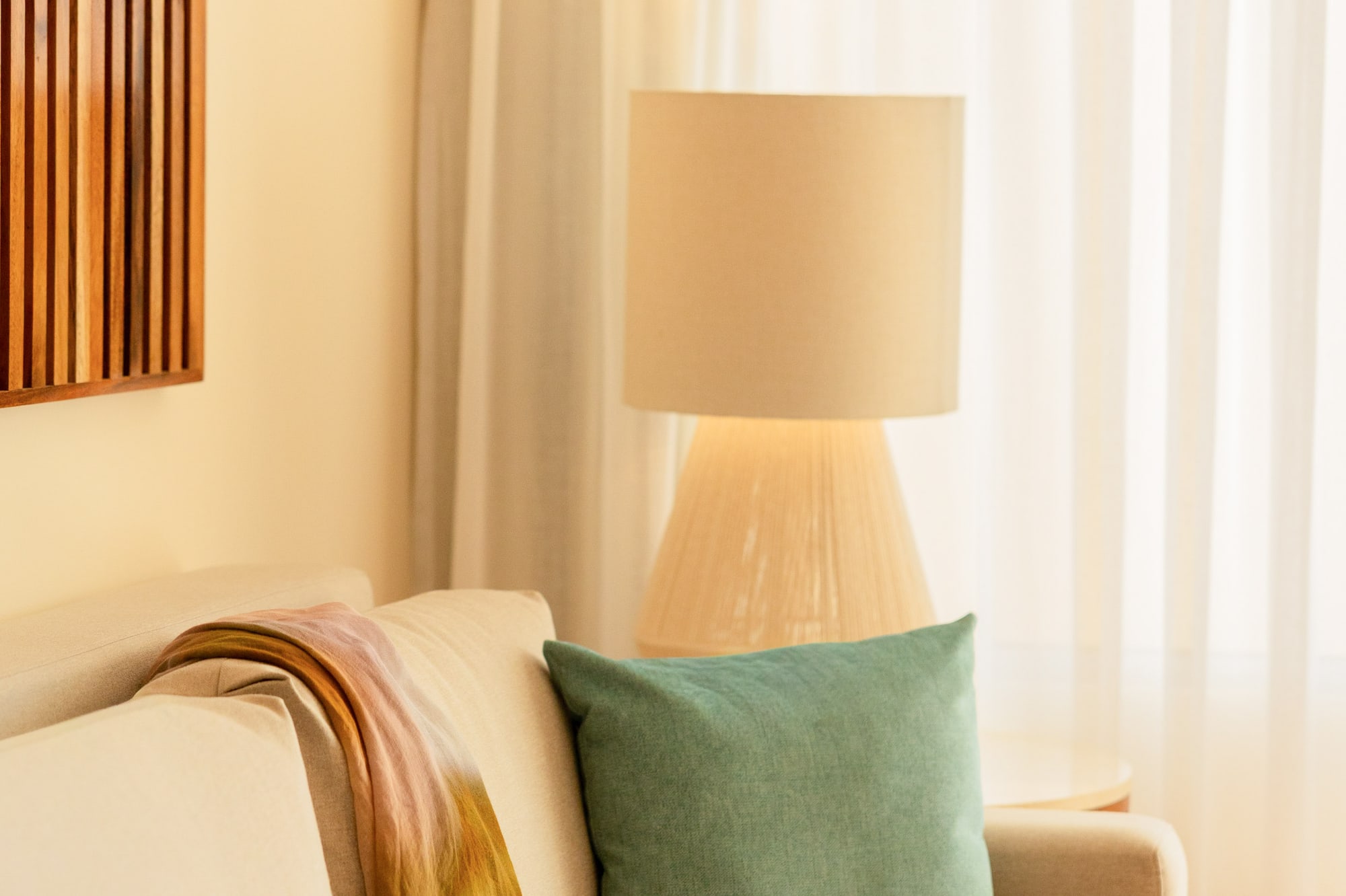 Cozy living room sofa with colorful throw, teal pillow, and soft lamp light.