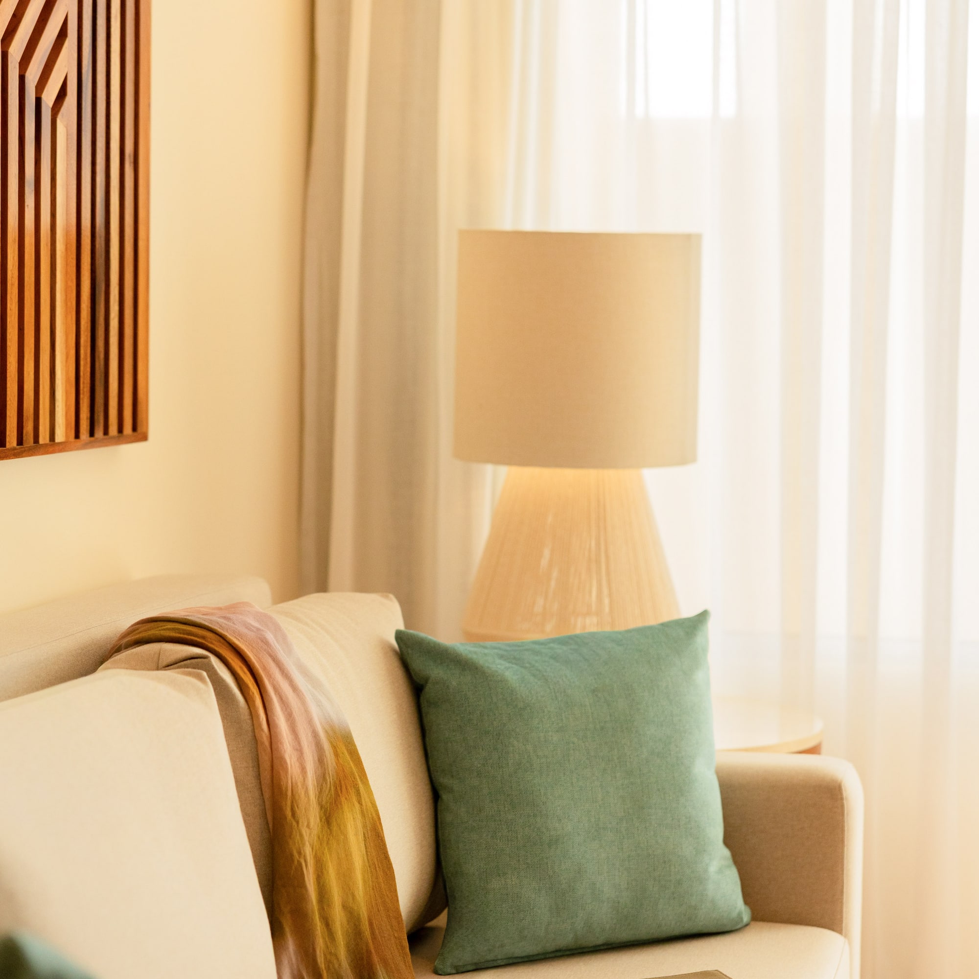 Cozy living room sofa with colorful throw, teal pillow, and soft lamp light.