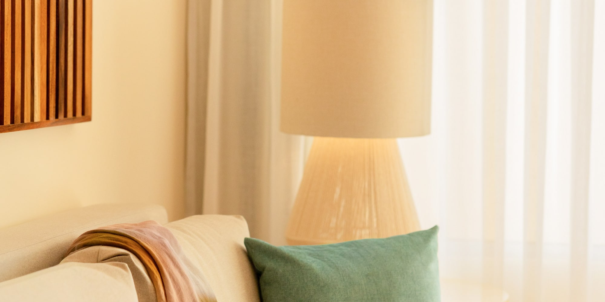 Cozy living room sofa with colorful throw, teal pillow, and soft lamp light.