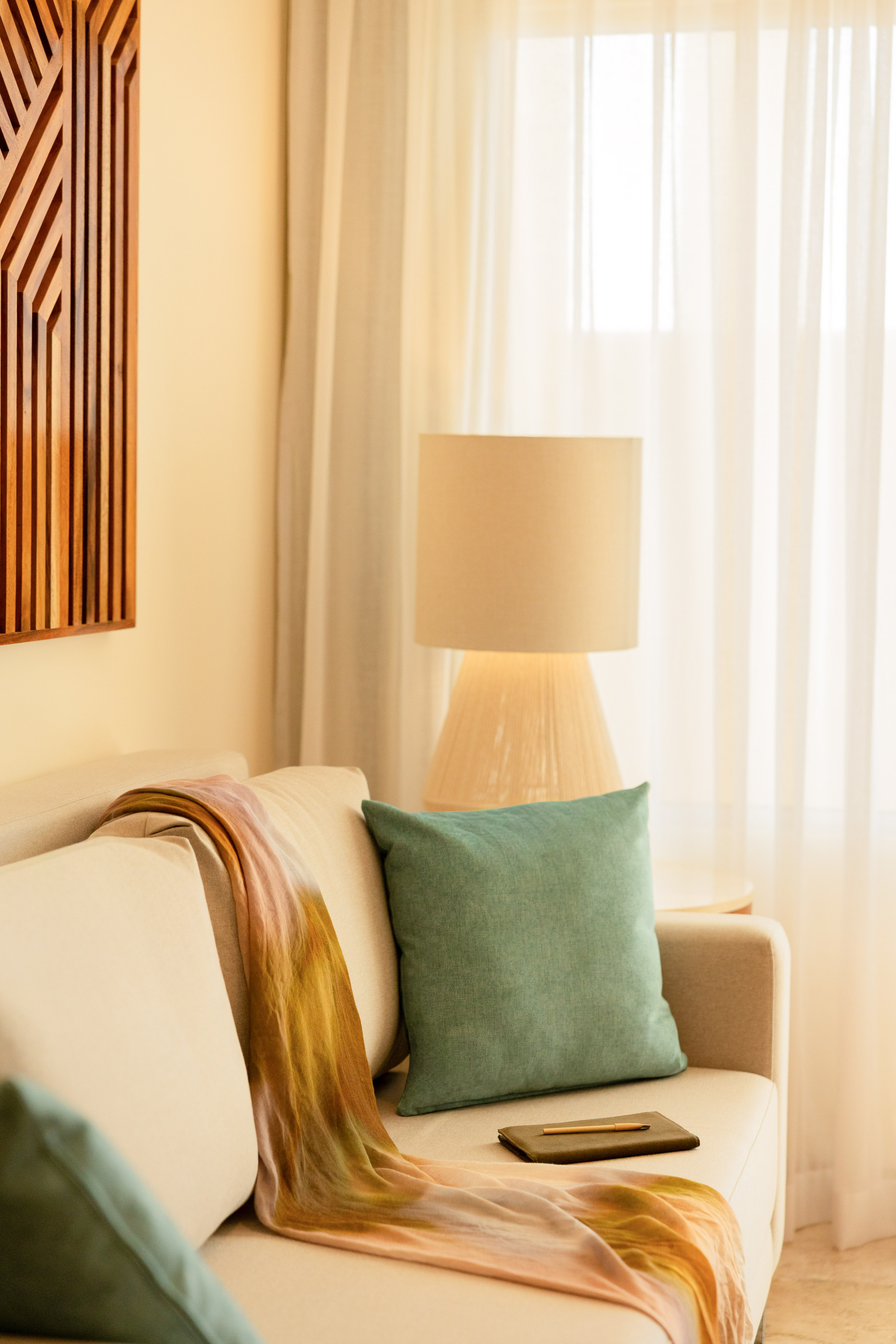 Cozy living room sofa with colorful throw, teal pillow, and soft lamp light.