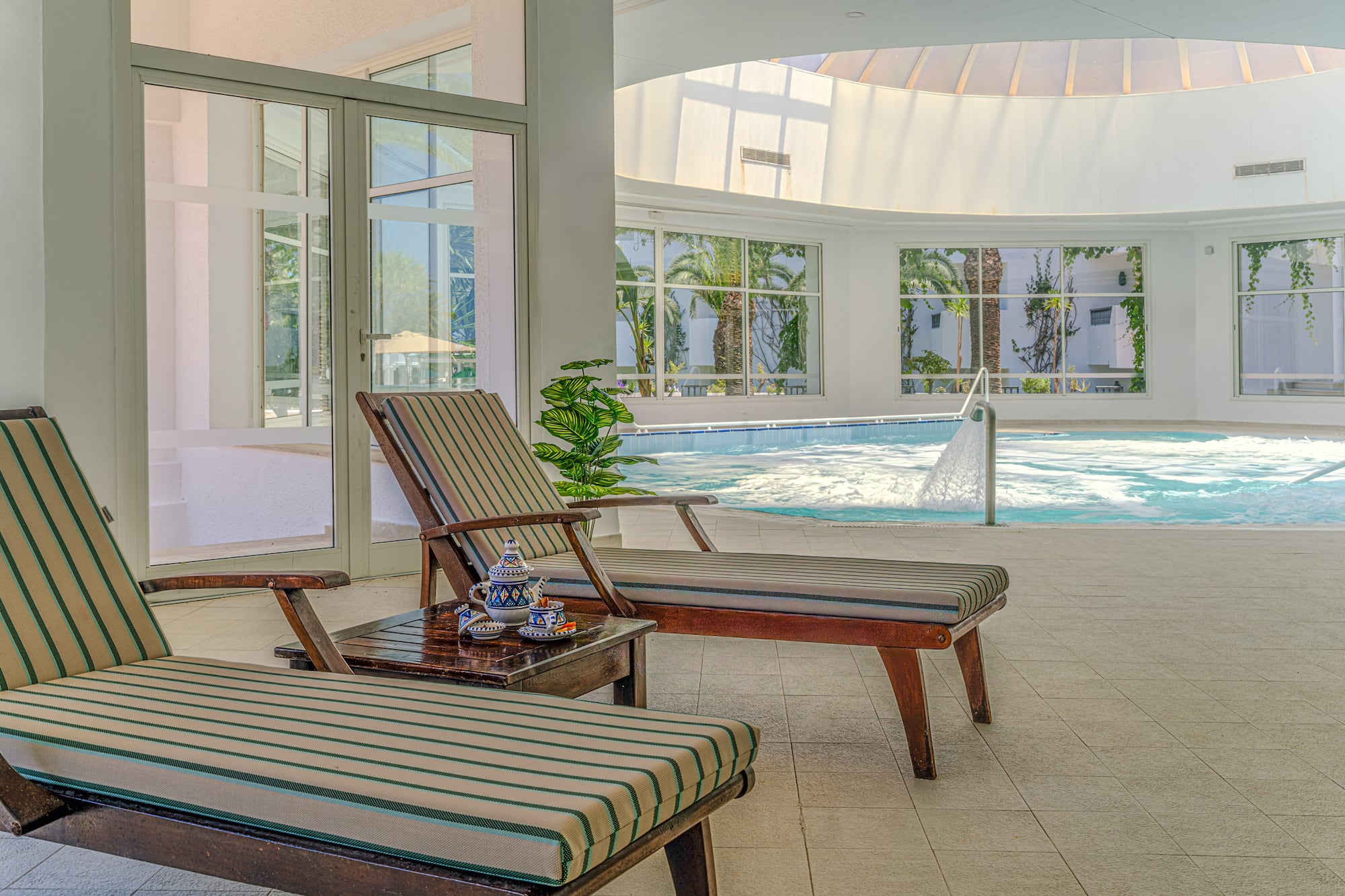 Indoor spa lounge with chairs, bubbling jacuzzi, and natural light.