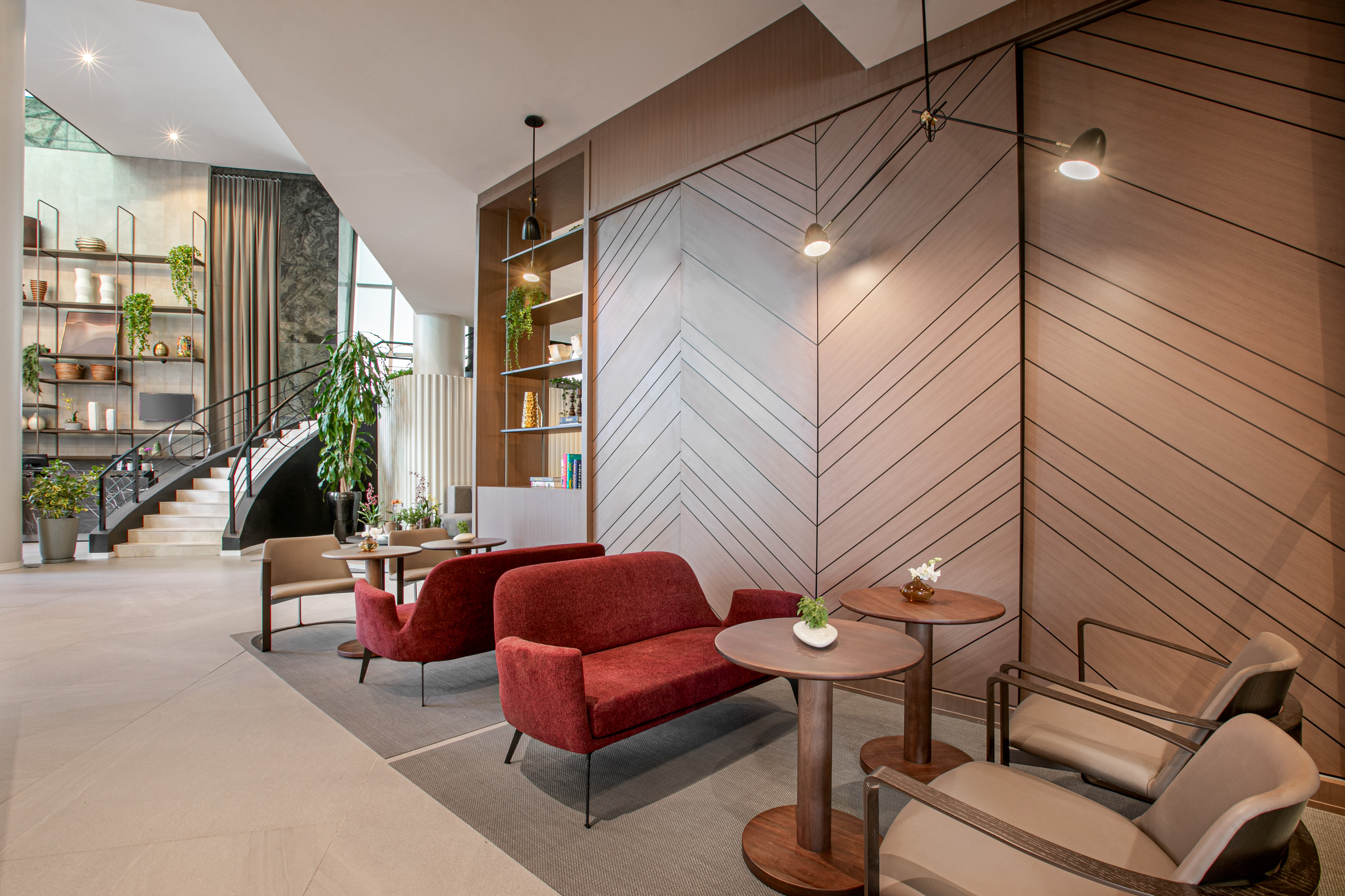 Modern lobby lounge interior with red sofas, wood paneling, and staircase.