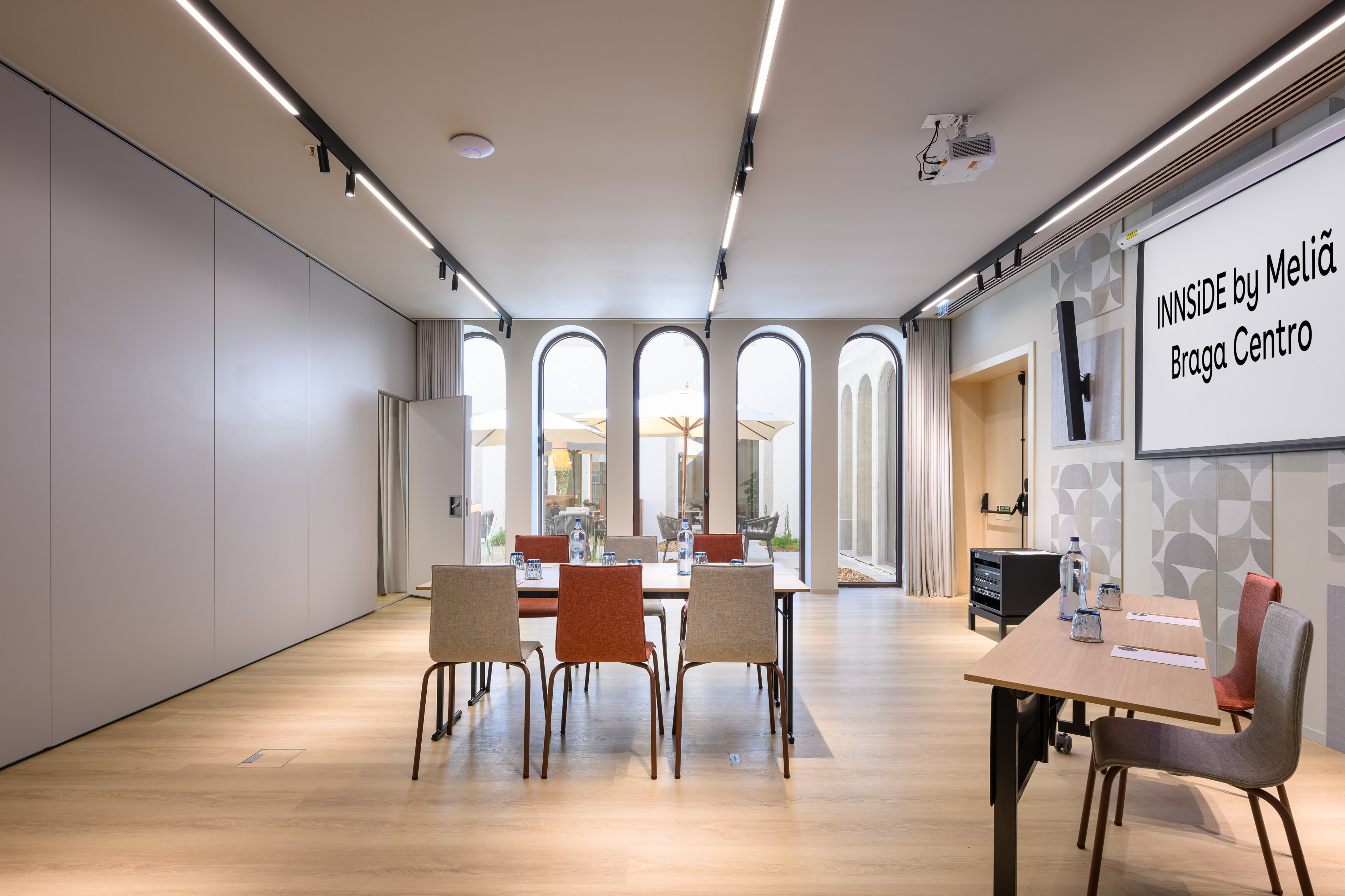 INNSiDE Braga Centro meeting room with projector, screen, and natural light.