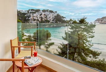 a chair and table with a glass fence overlooking a beach