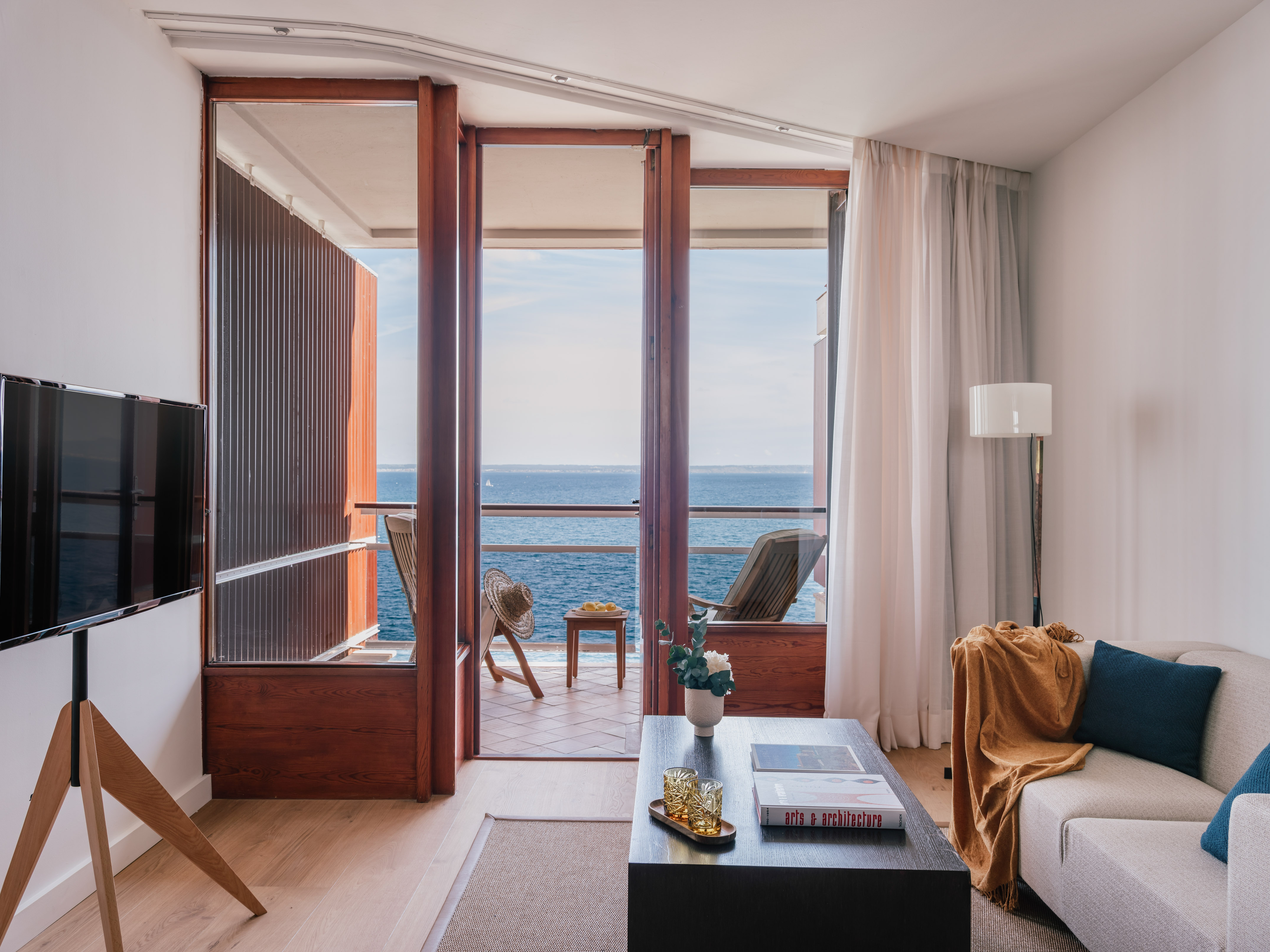 Modern living room with ocean view balcony, sofa, and coffee table.