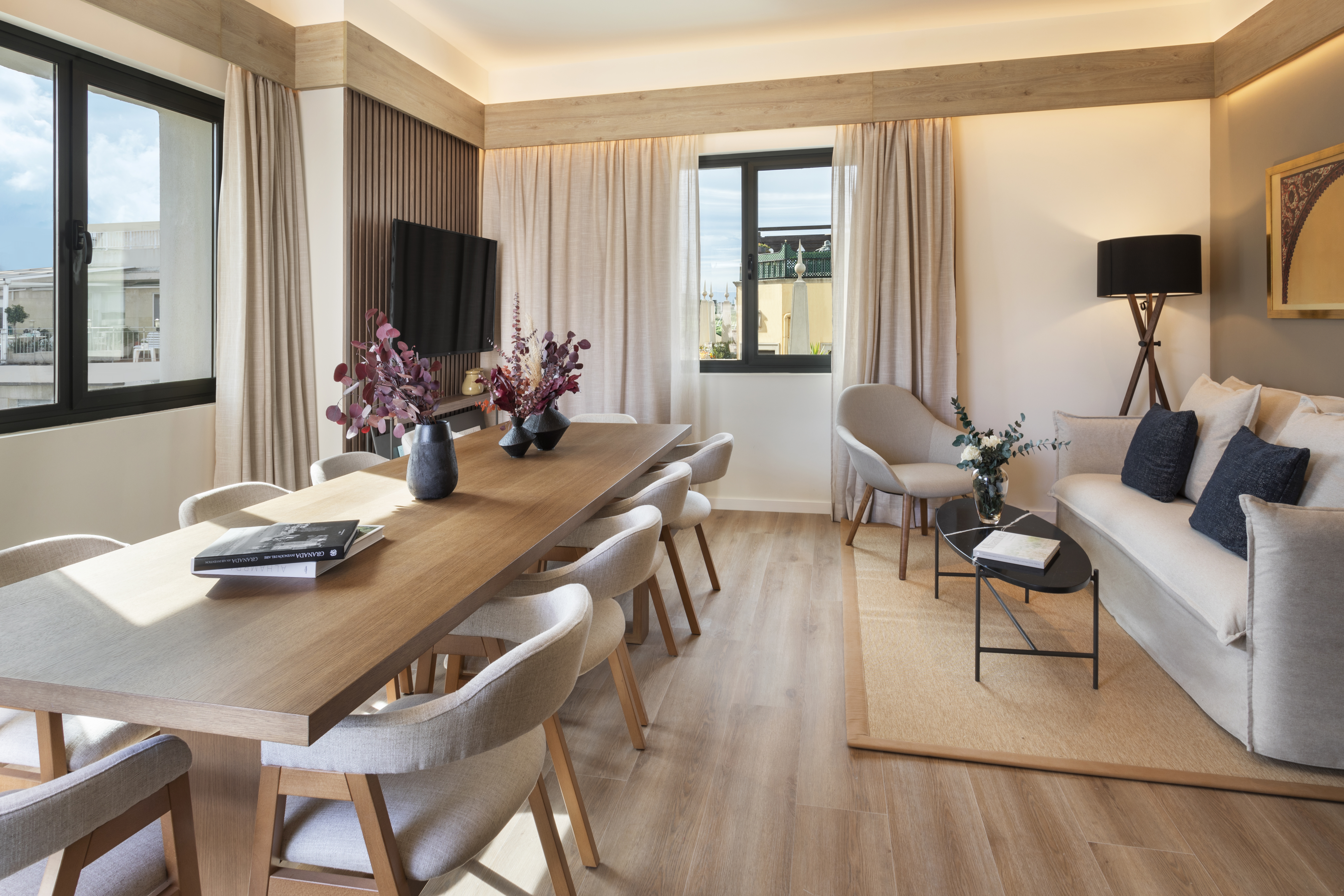 Contemporary hotel suite with dining table, living room sofa, neutral decor.