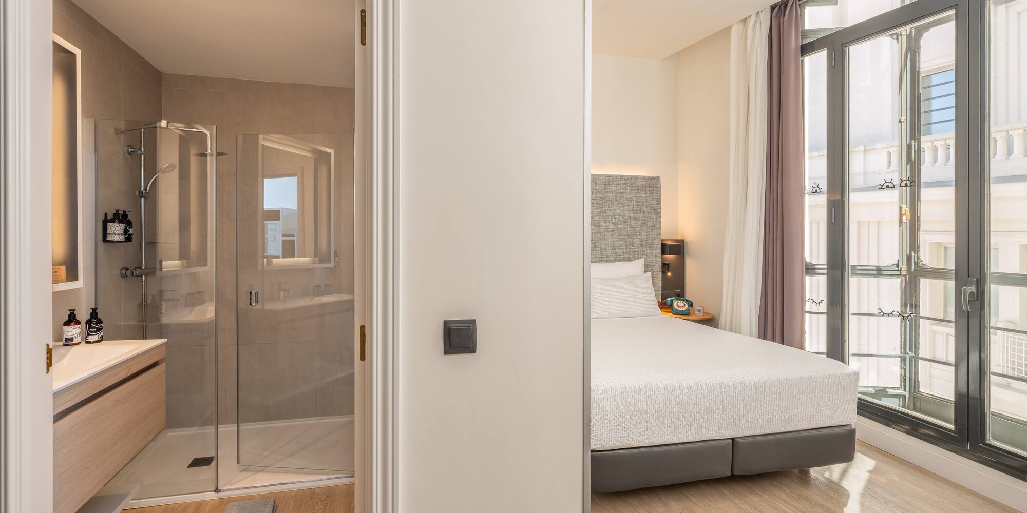 Modern hotel room with a bedroom, en-suite bathroom, and walk-in shower.