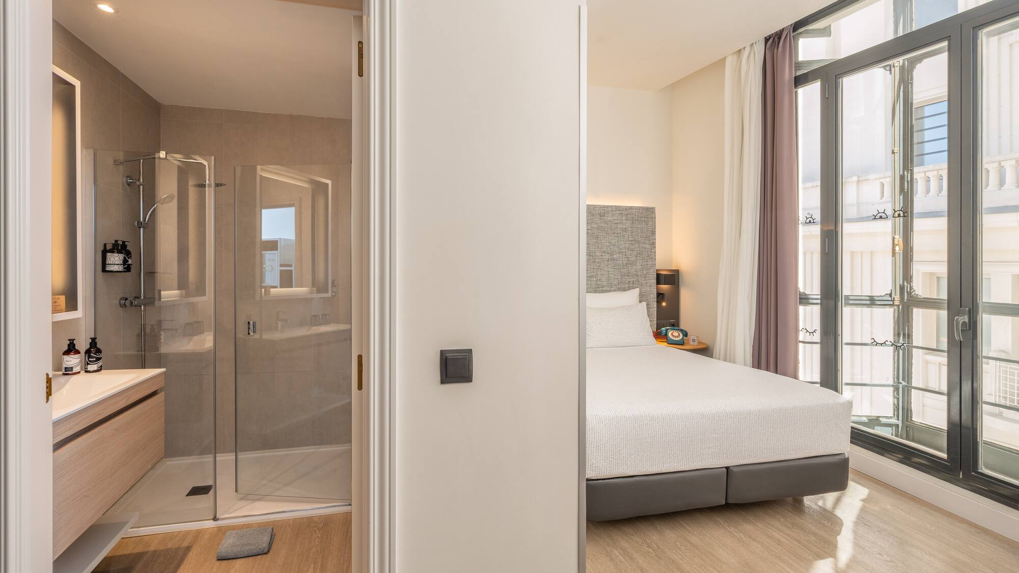 Modern hotel room with a bedroom, en-suite bathroom, and walk-in shower.