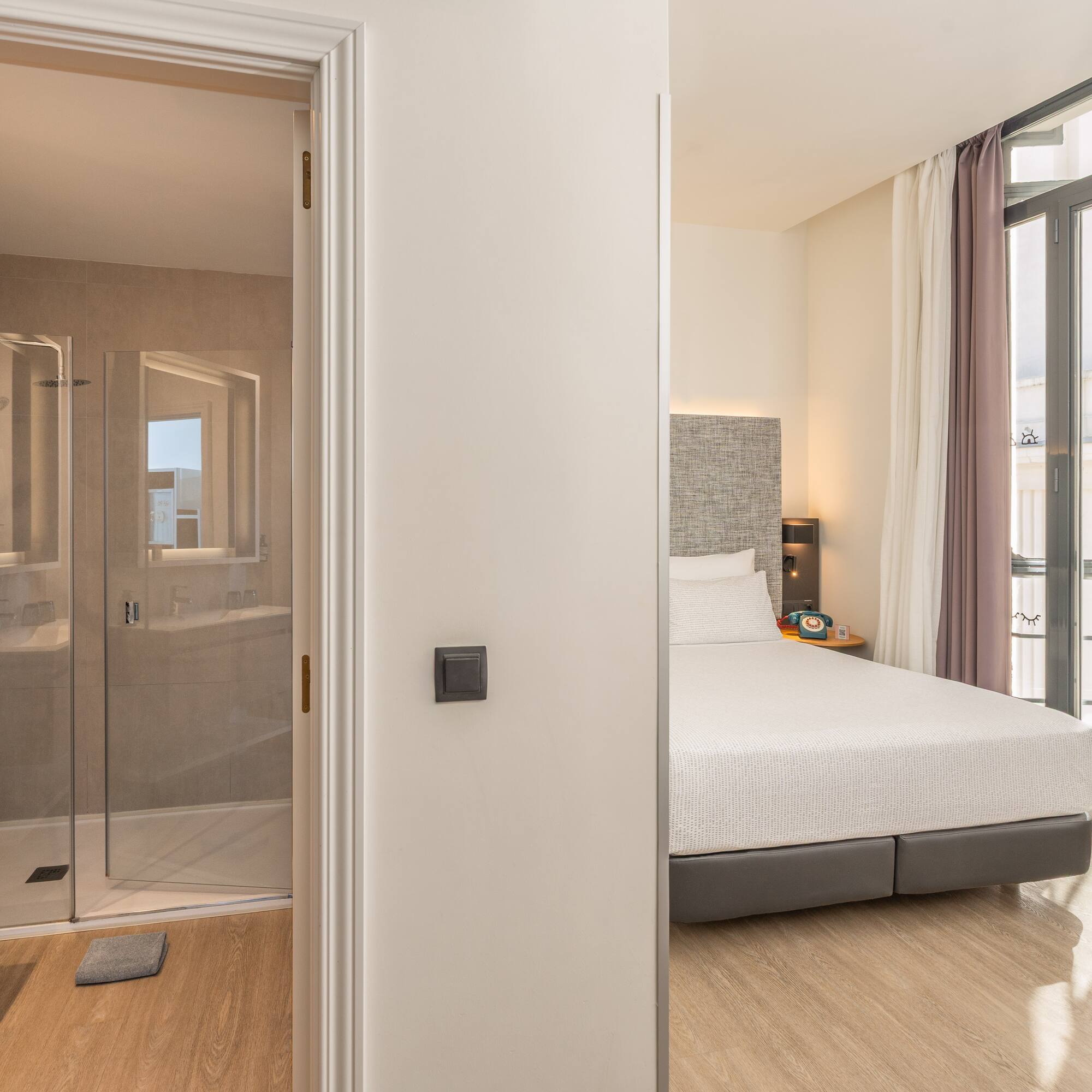 Modern hotel room with a bedroom, en-suite bathroom, and walk-in shower.