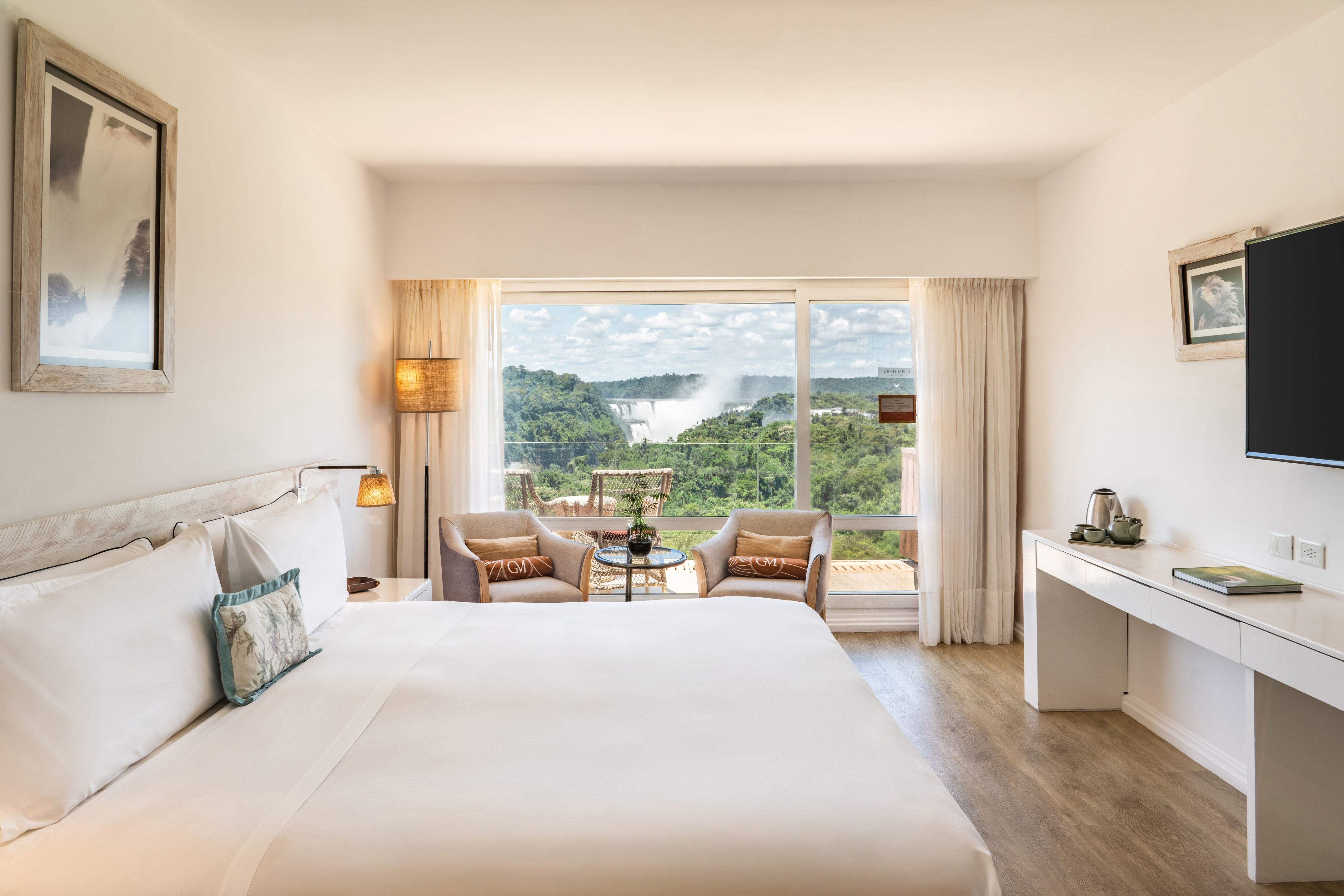 a room with a large bed and a table with chairs and a table with a view of the mountains
