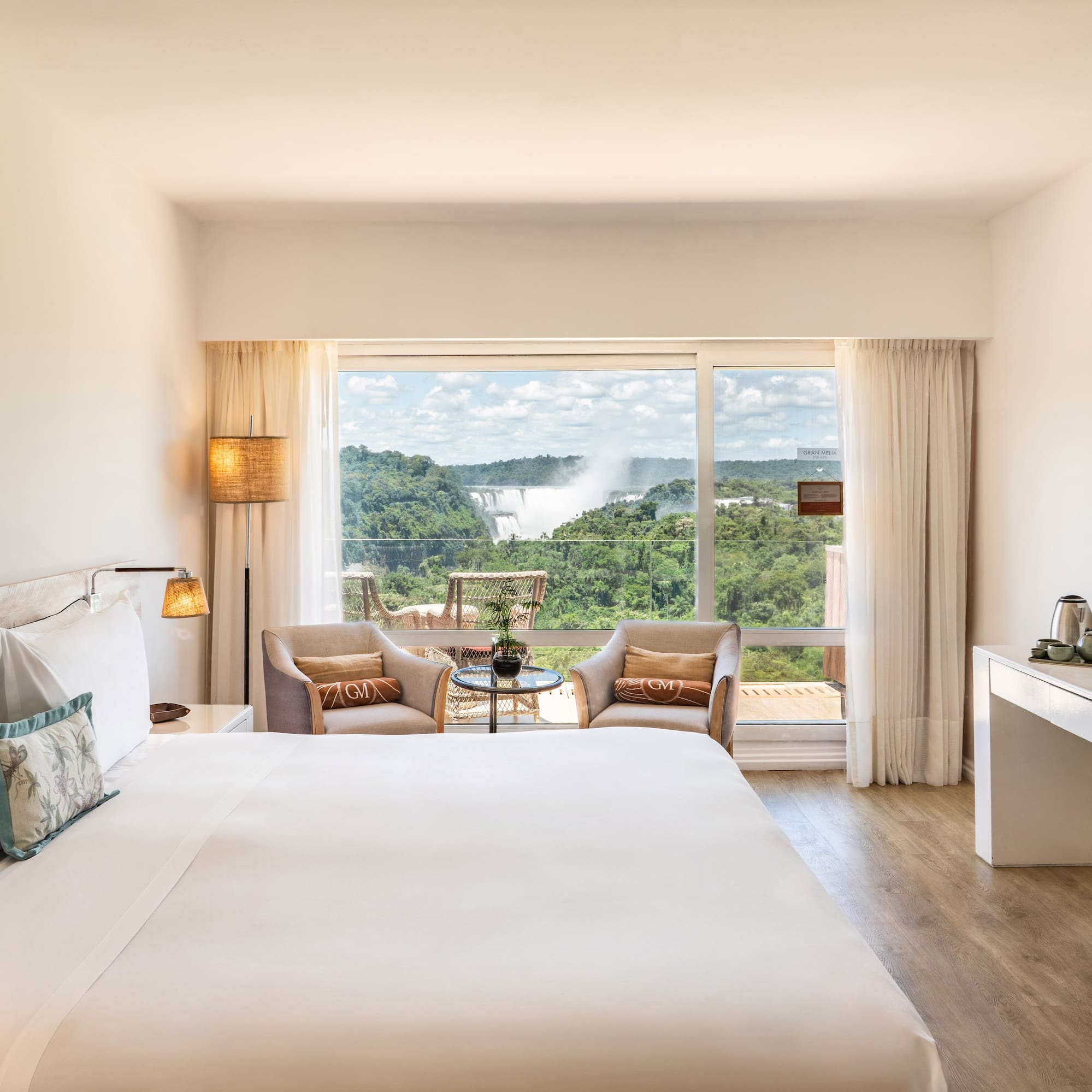 a room with a large bed and a table with chairs and a table with a view of the mountains