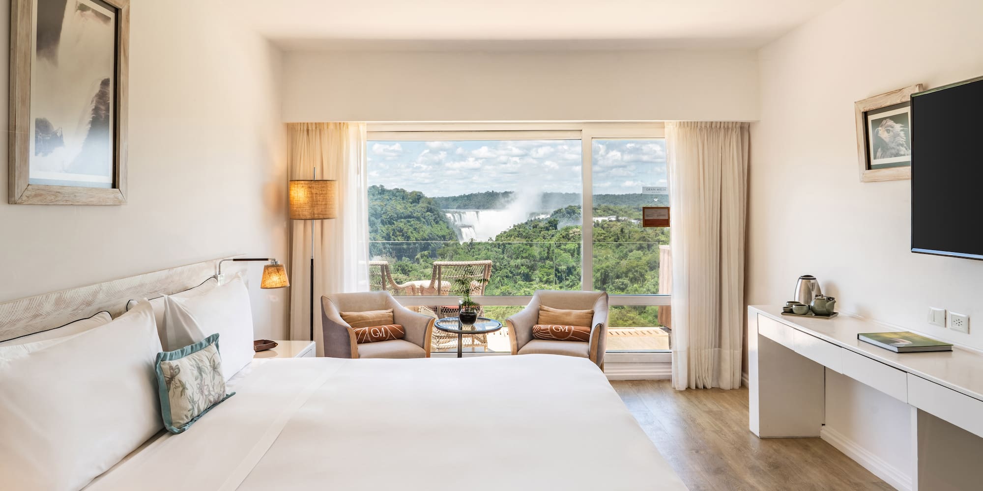 a room with a large bed and a table with chairs and a table with a view of the mountains