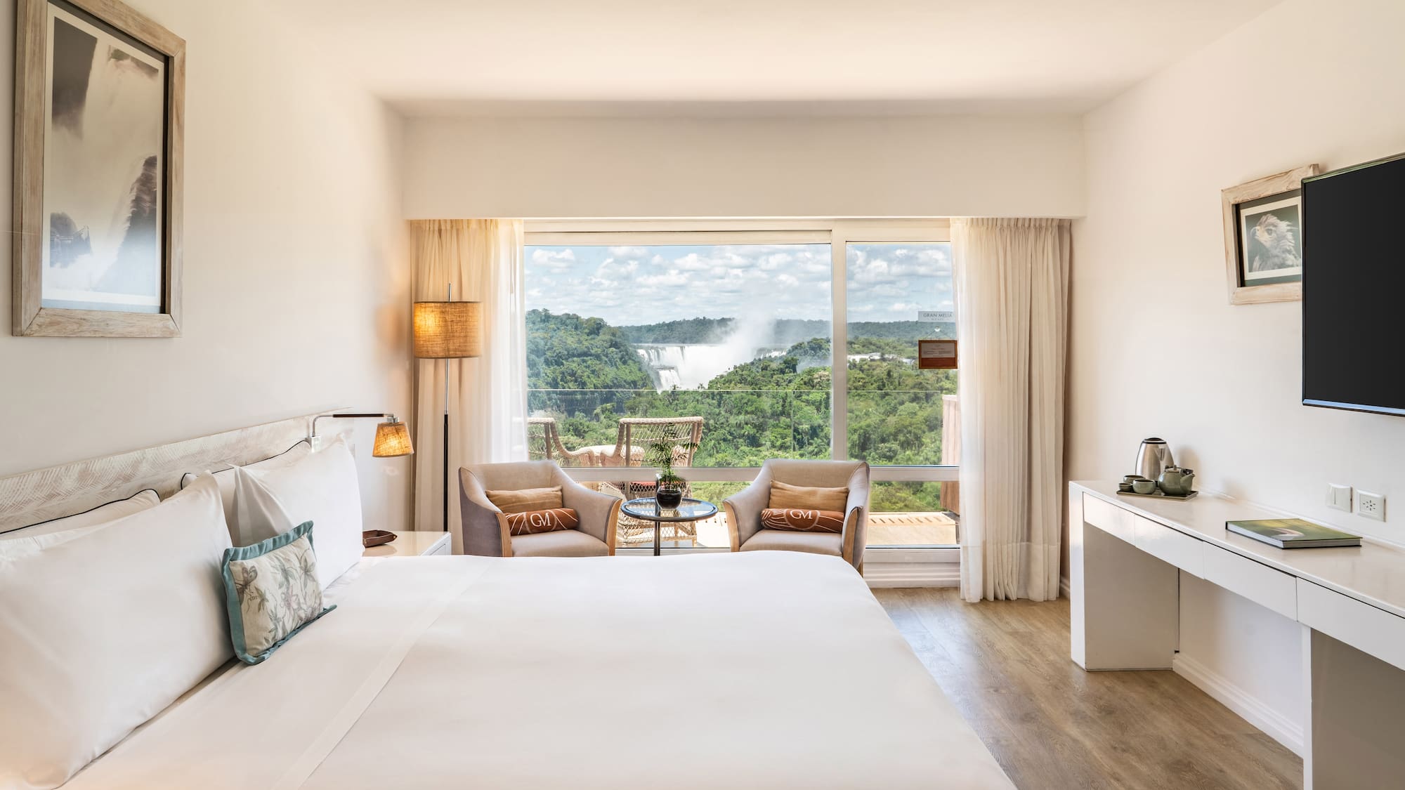 a room with a large bed and a table with chairs and a table with a view of the mountains