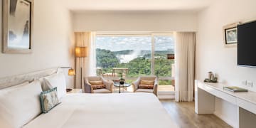 a room with a large bed and a table with chairs and a table with a view of the mountains