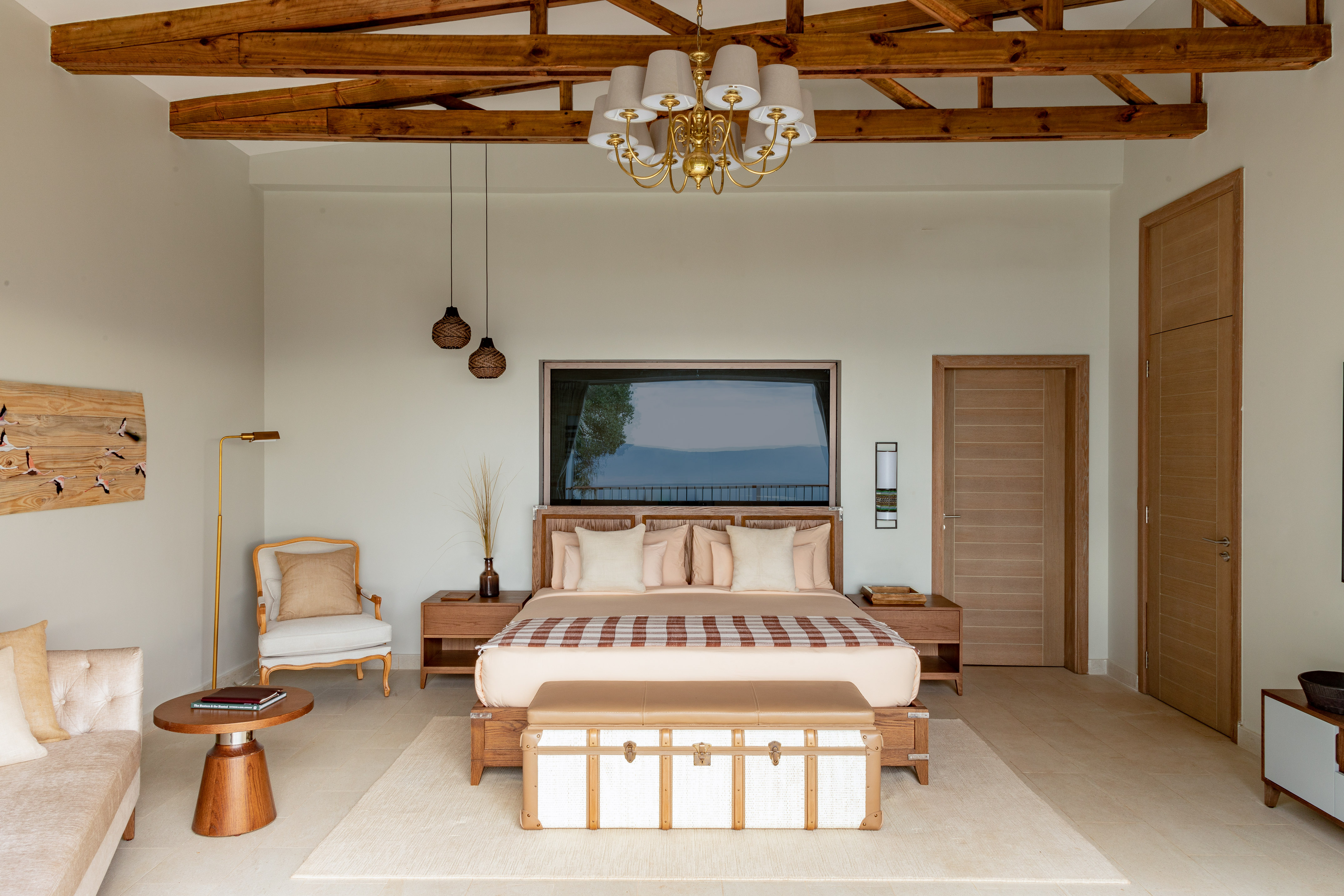 Elegant modern bedroom with large bed, wood beams, and gold chandelier.
