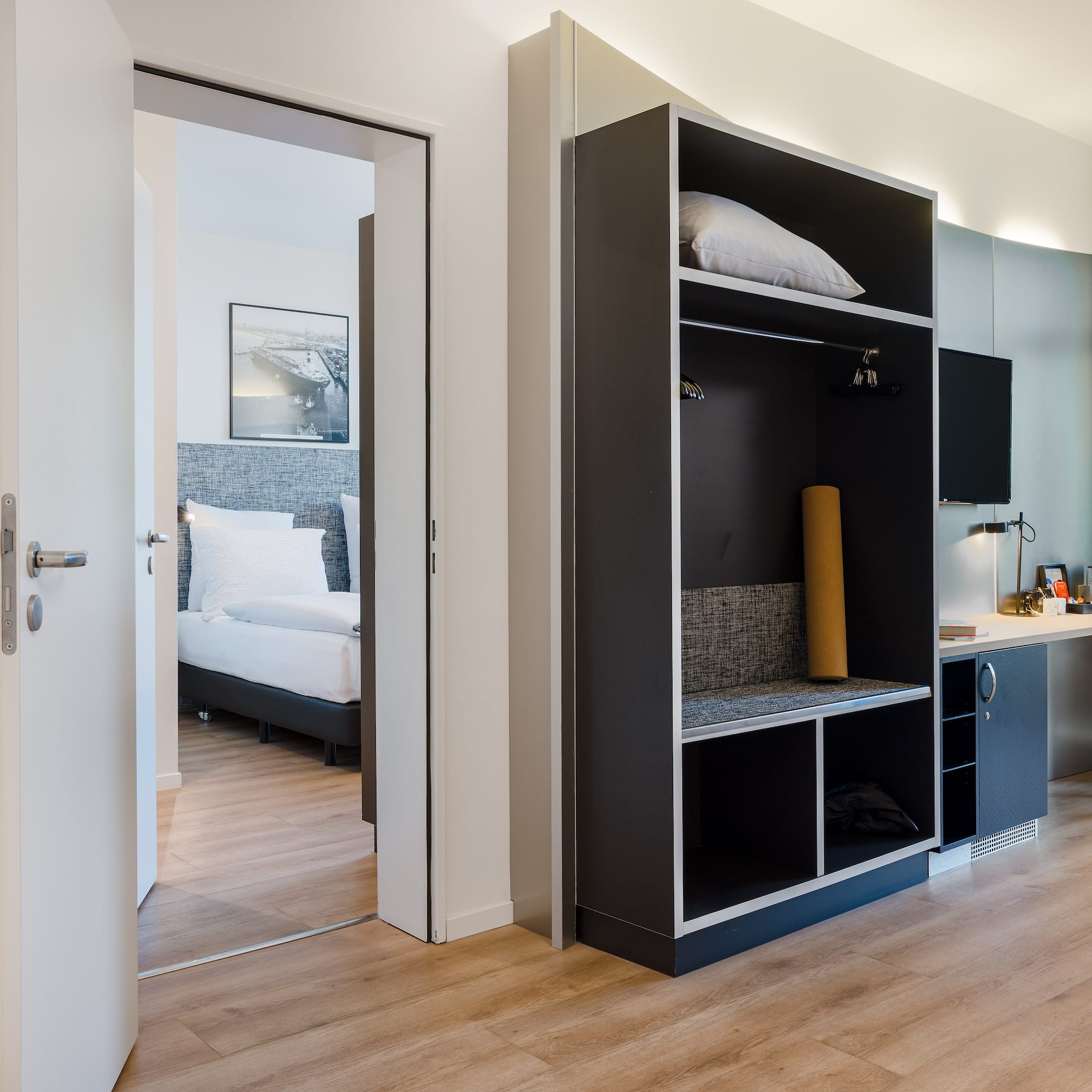 Modern hotel room interior: open wardrobe, work desk, adjoining bedroom.