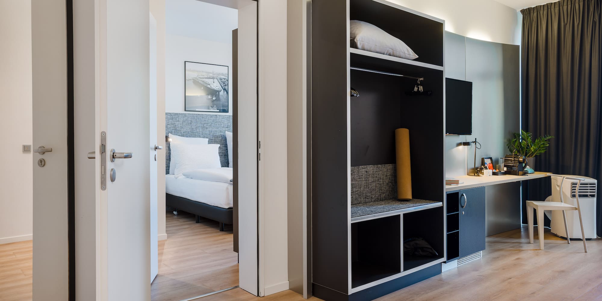 Modern hotel room interior: open wardrobe, work desk, adjoining bedroom.
