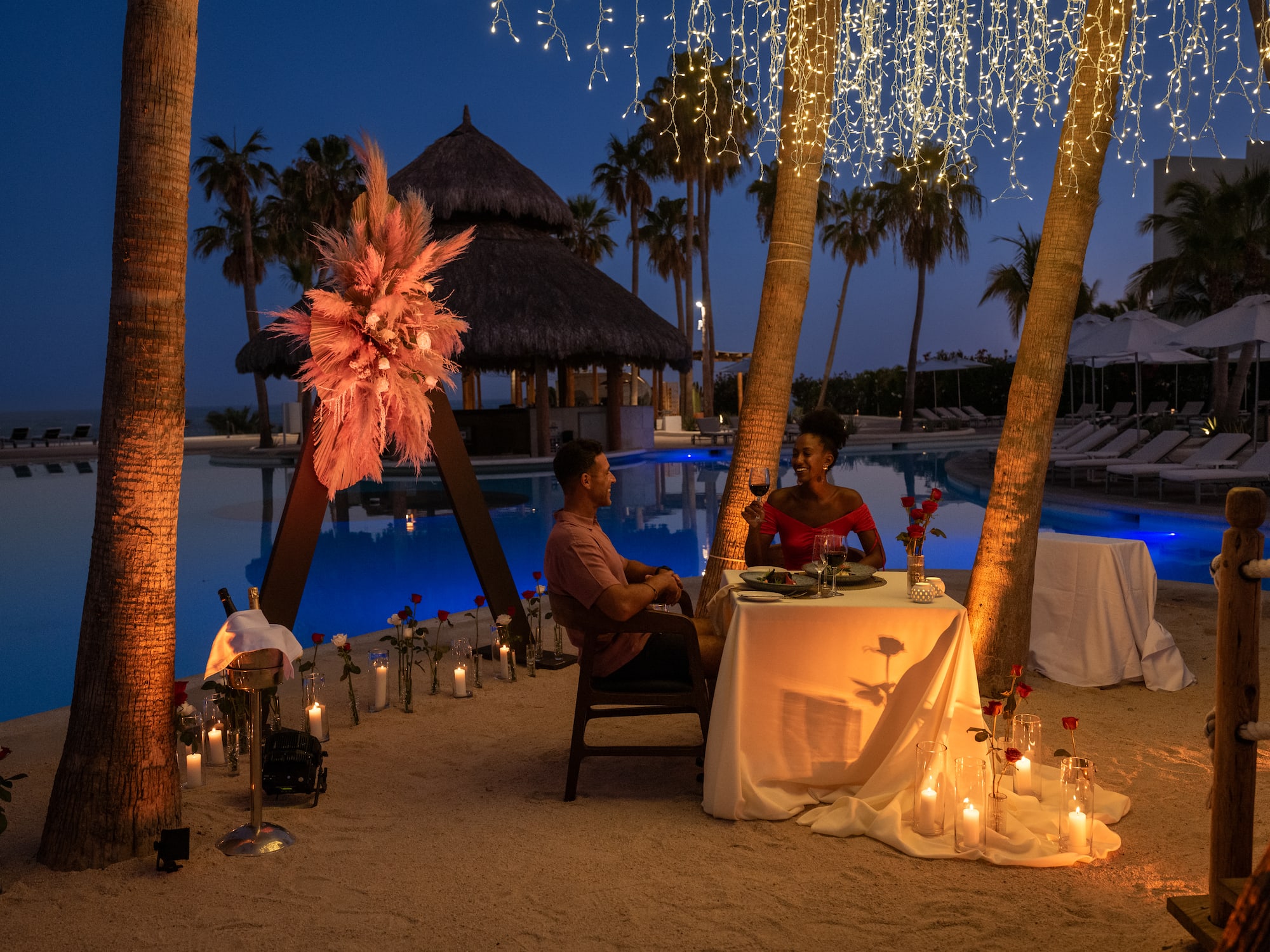 a man and woman sitting at a table under a pool with lights