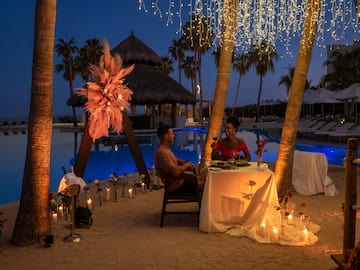 a man and woman sitting at a table under a pool with lights