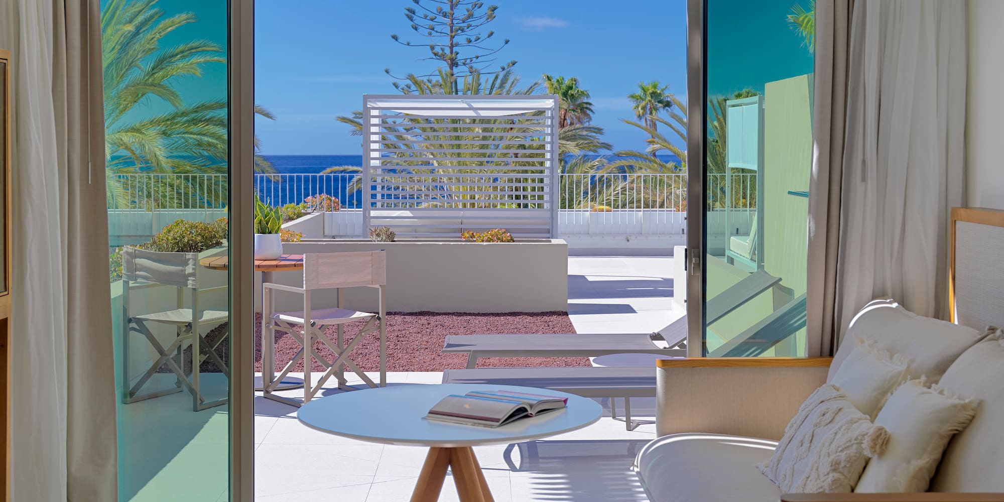 a room with a view of the ocean and a couch and a table