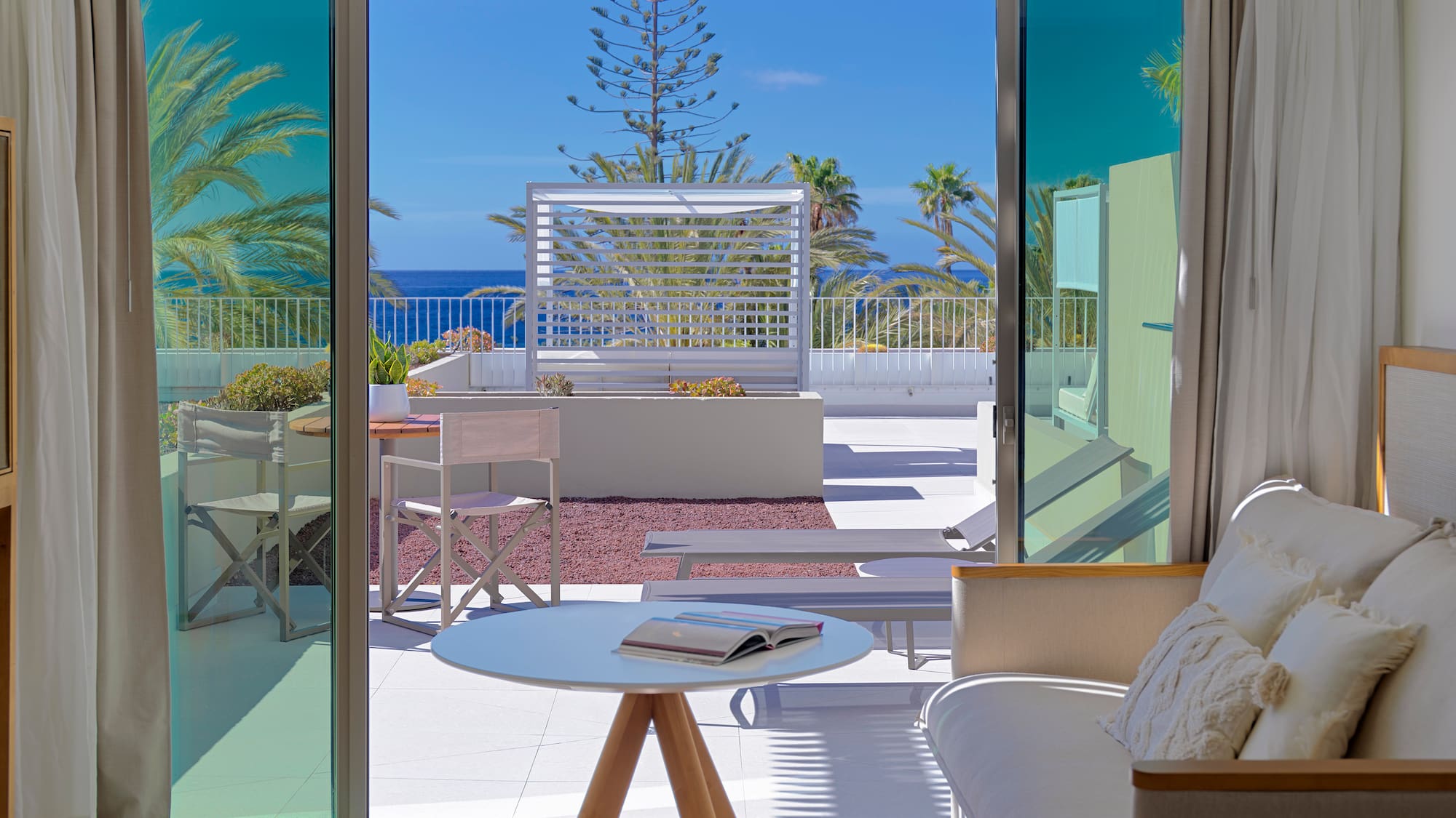 a room with a view of the ocean and a couch and a table
