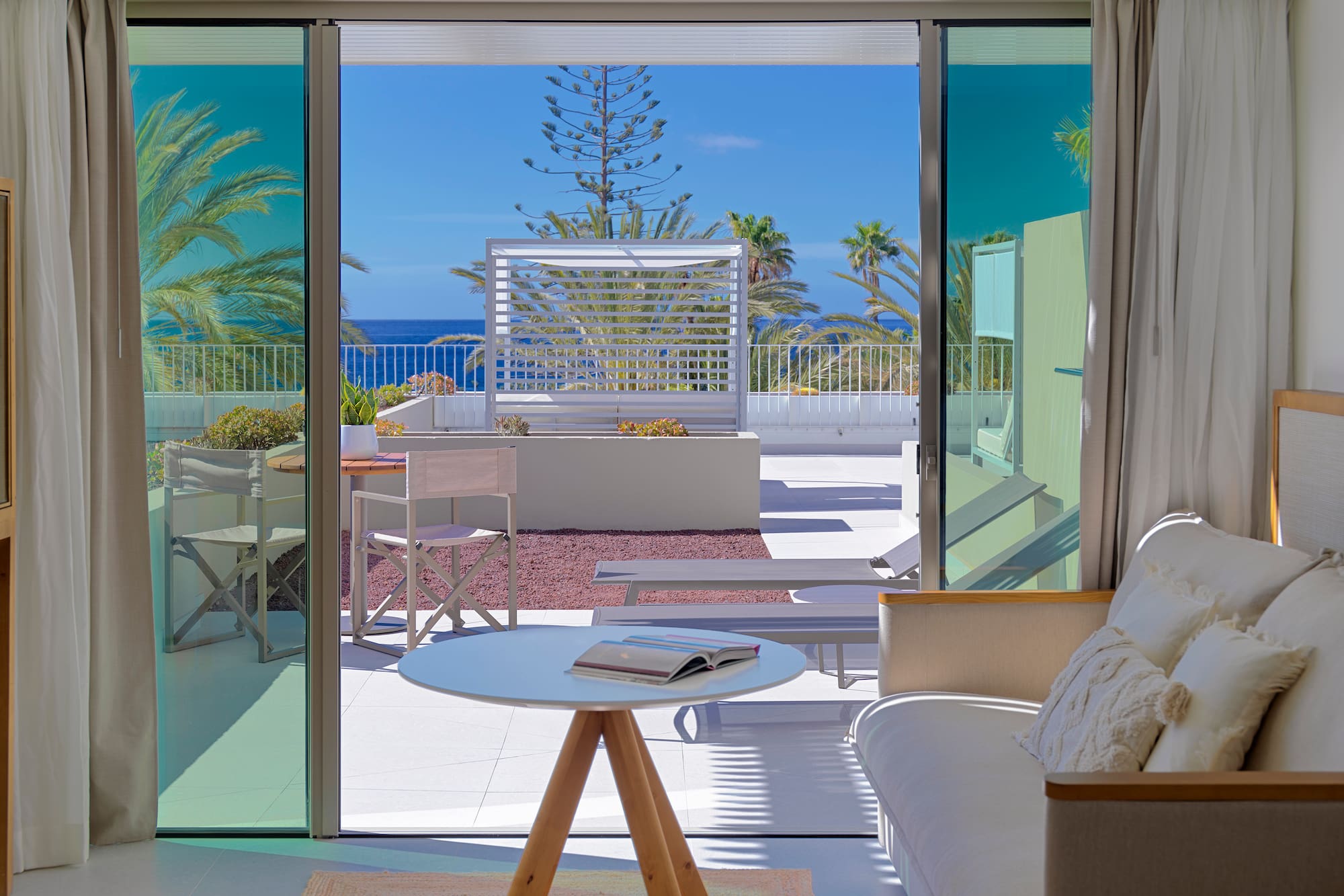a room with a view of the ocean and a couch and a table