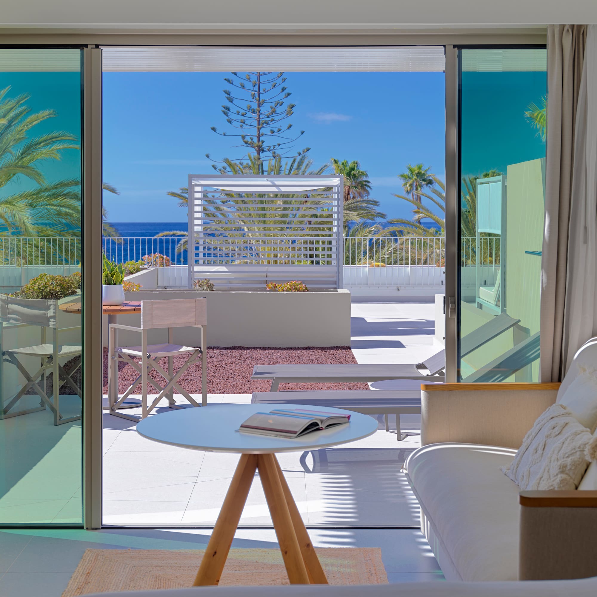 a room with a view of the ocean and a couch and a table