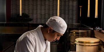 a man in a chef's uniform cutting food