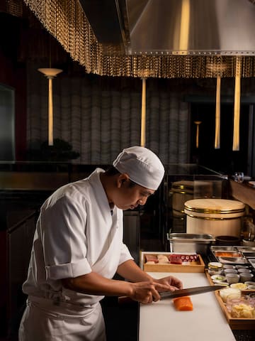 a man in a chef's uniform cutting food