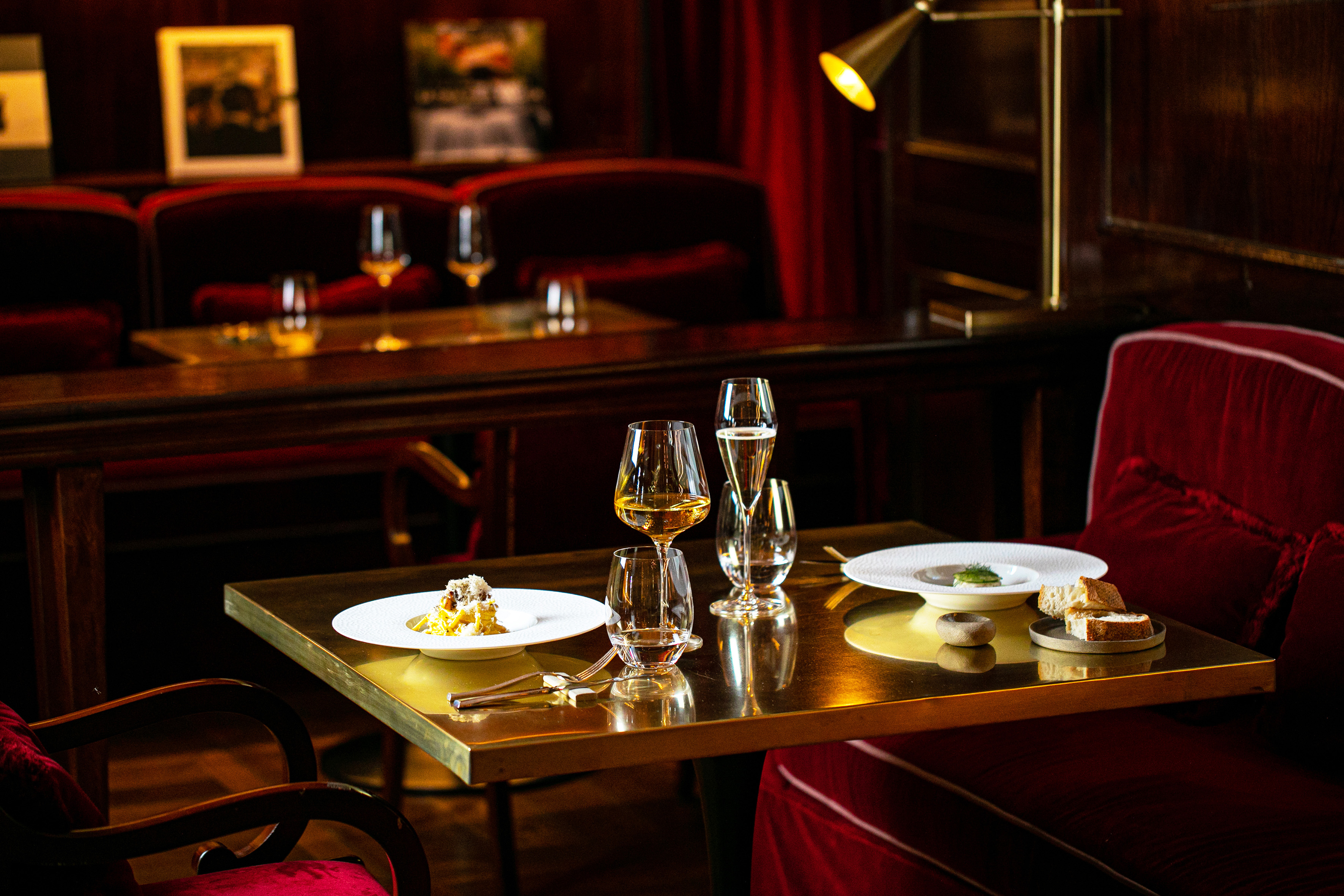 Luxury dining table with fine dishes, wine, champagne, red velvet chairs.